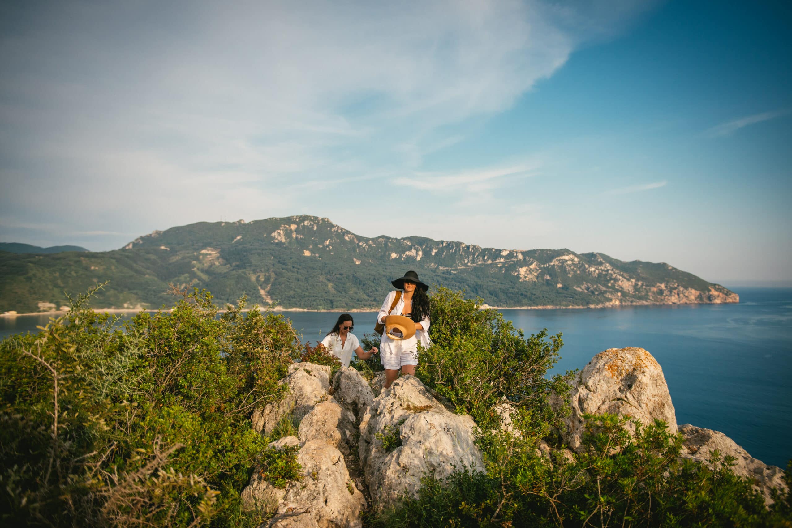 Brides gracefully walking on the rocky terrain, embracing the natural beauty of Corfu.