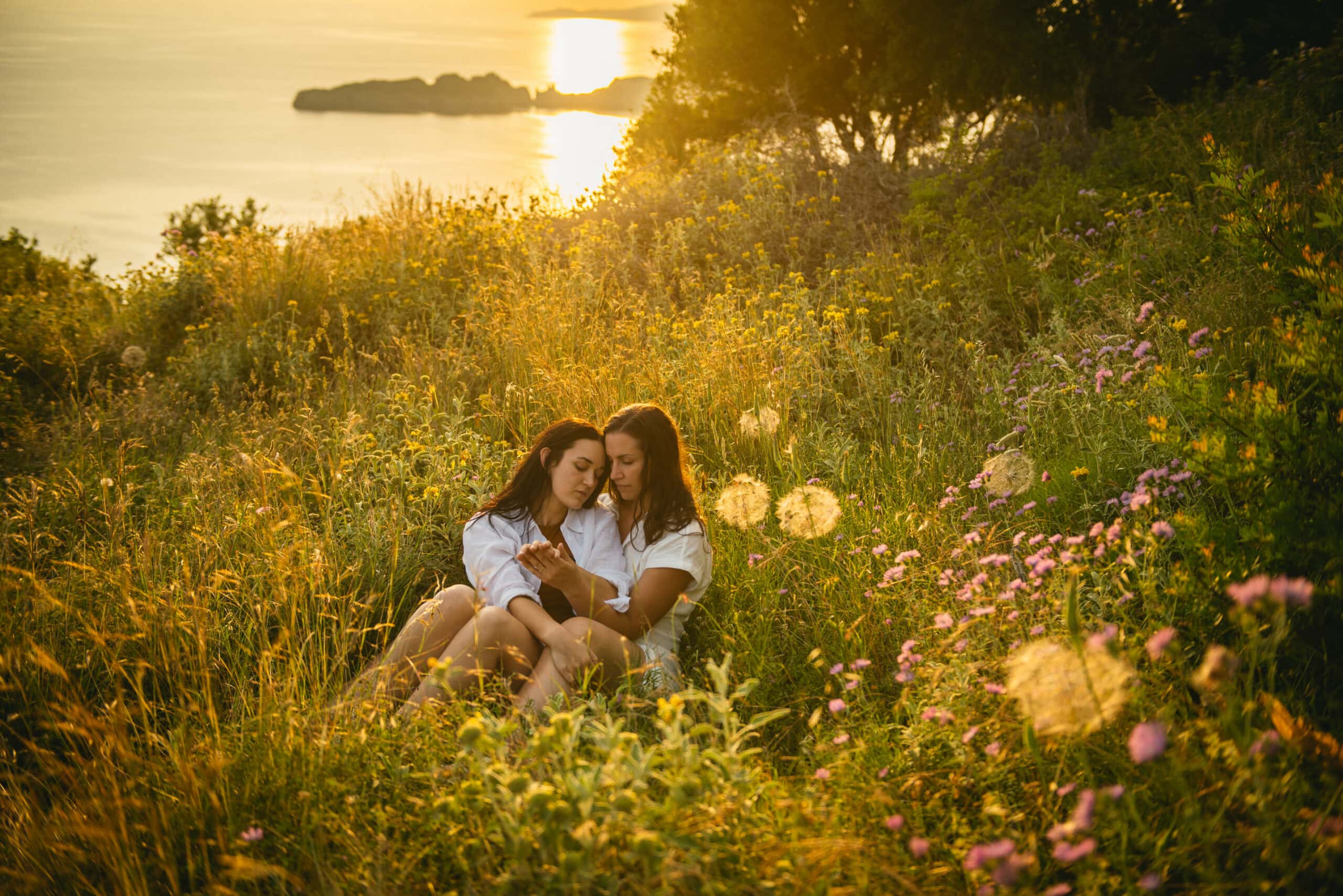Brides enjoying a serene moment, seated amidst the lush grass during their Corfu elopement.