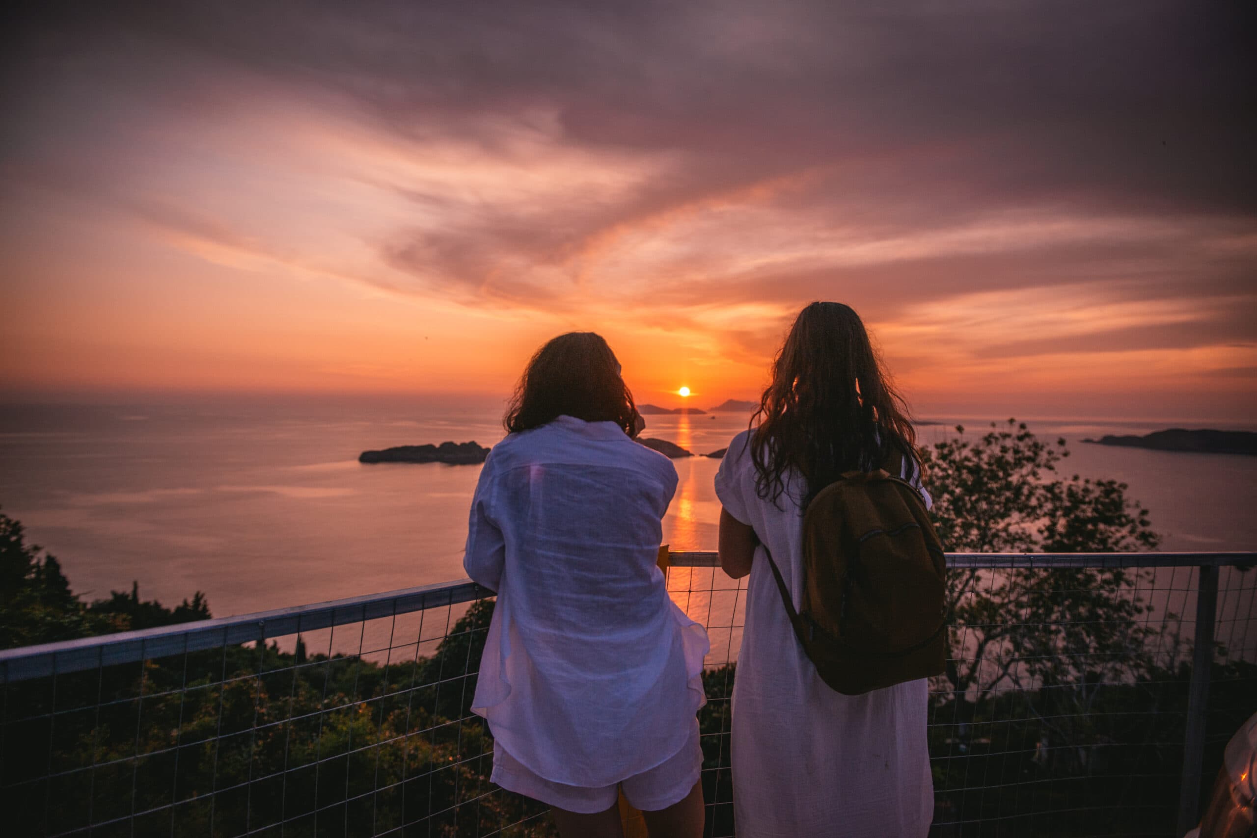 Brides gazing at the mesmerizing sunset, a shared moment of tranquility during their Corfu elopement.
