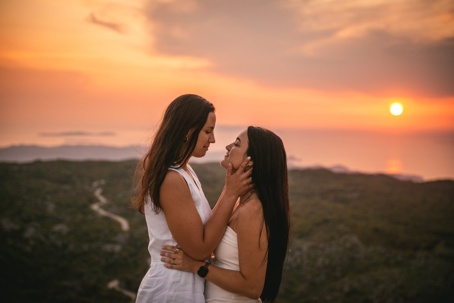 Twilight's tender touch: Brides stand against the sunset, twilight's warmth embracing their love during their Corfu elopement.