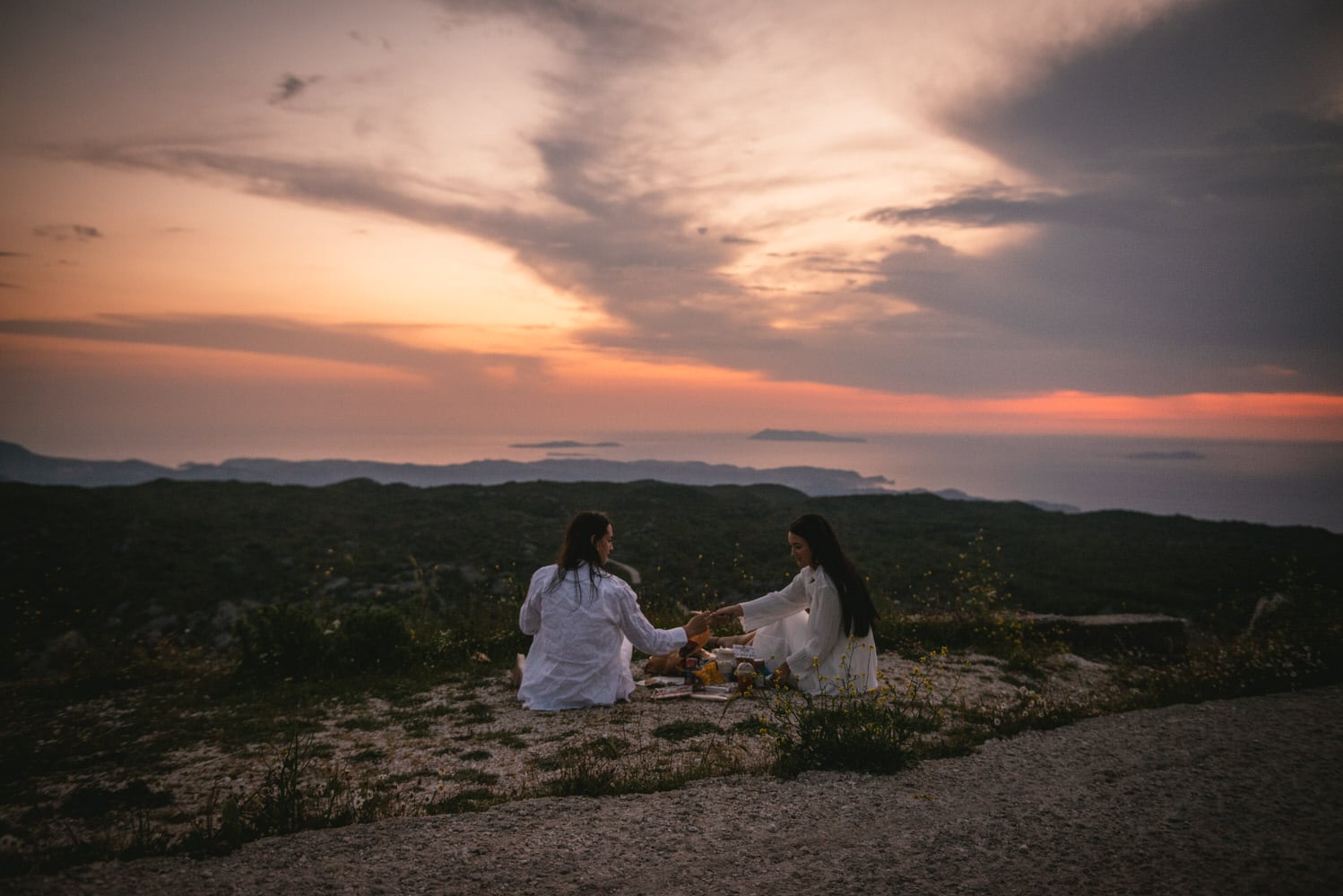 Love conquers closed roads: Brides enjoy a picnic on Mount Pantokrator's summit during their Corfu elopement.