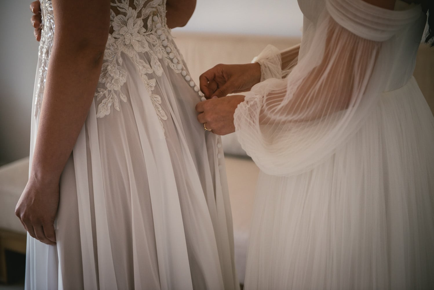 Bride's hands gracefully fastening the dress, anticipation for their Corfu elopement.