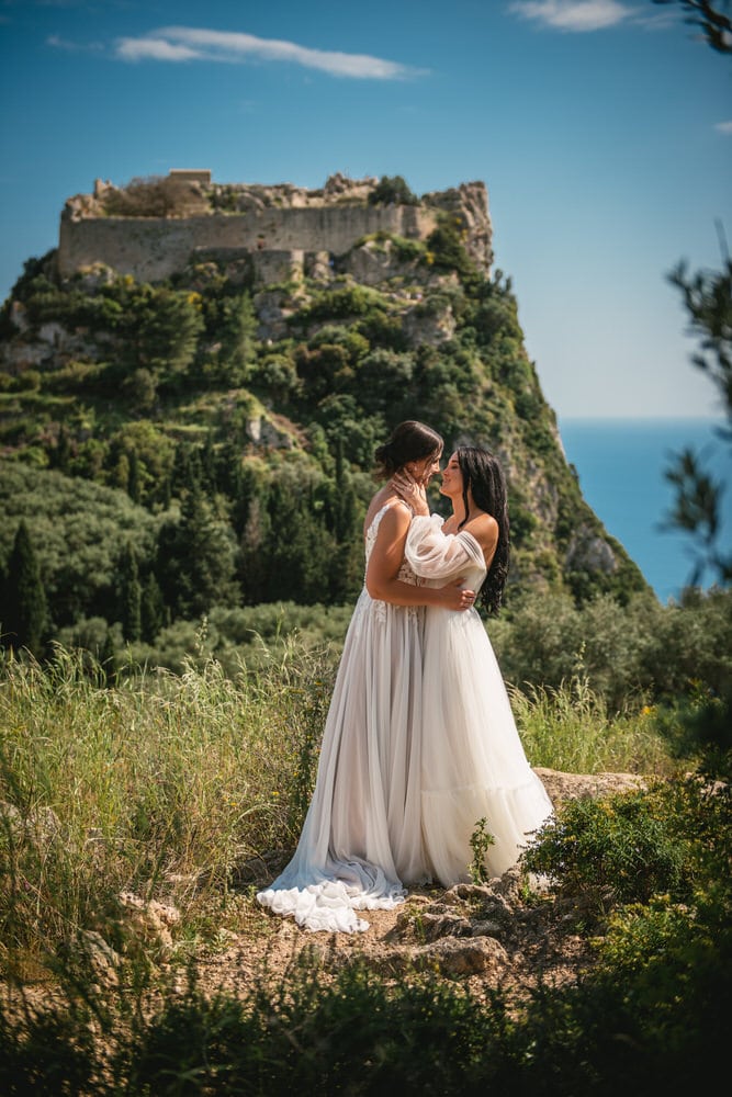 Brides sharing a kiss in front of a romantic ruined castle, Corfu elopement bliss.