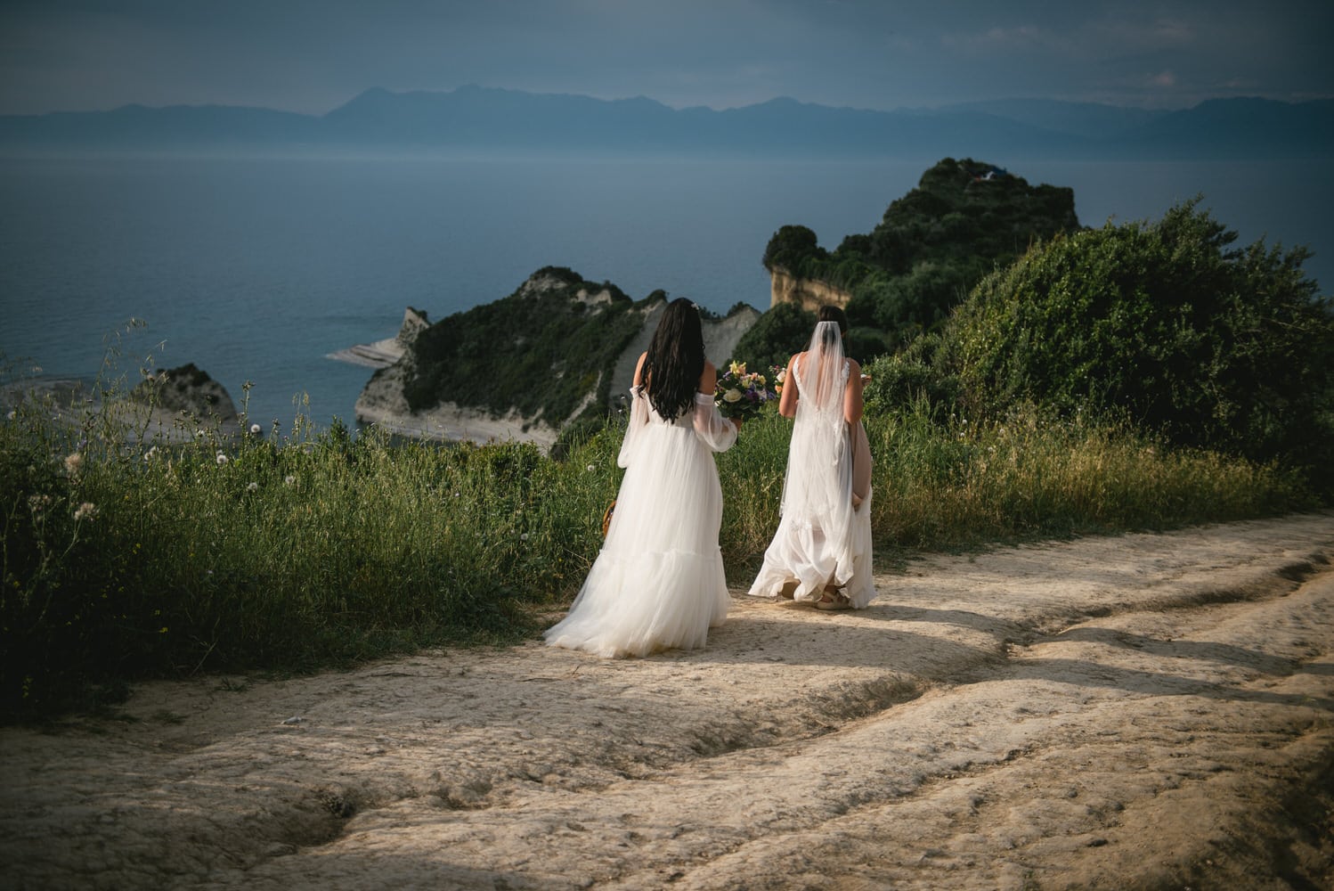 Brides walking on the cliff's edge, courage and love on their Corfu elopement.
