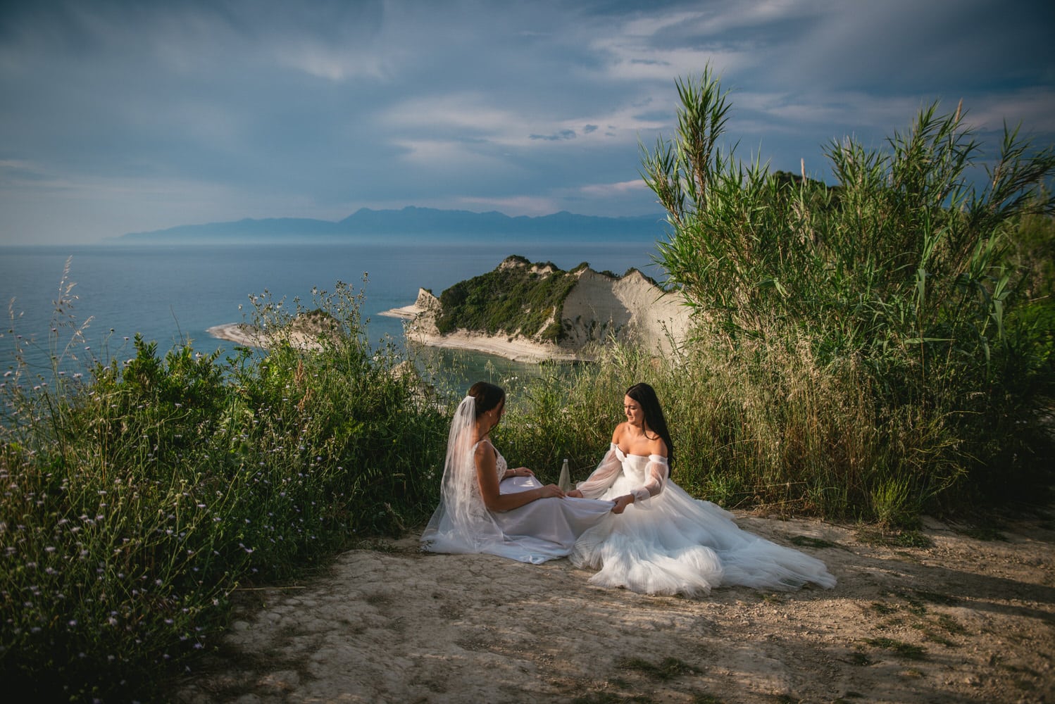 A breathtaking view: Brides embrace against a stunning clifftop seascape during their Corfu elopement.