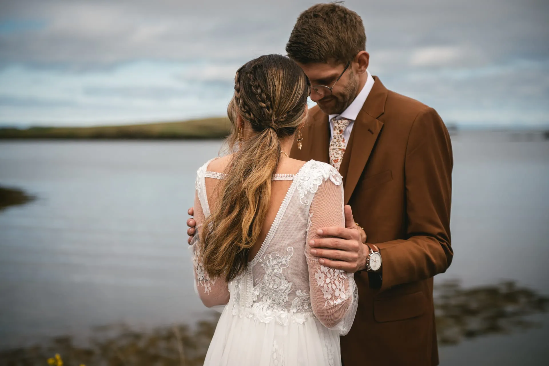Bride and groom stand atop a cliff, overlooking the awe-inspiring Westfjords.