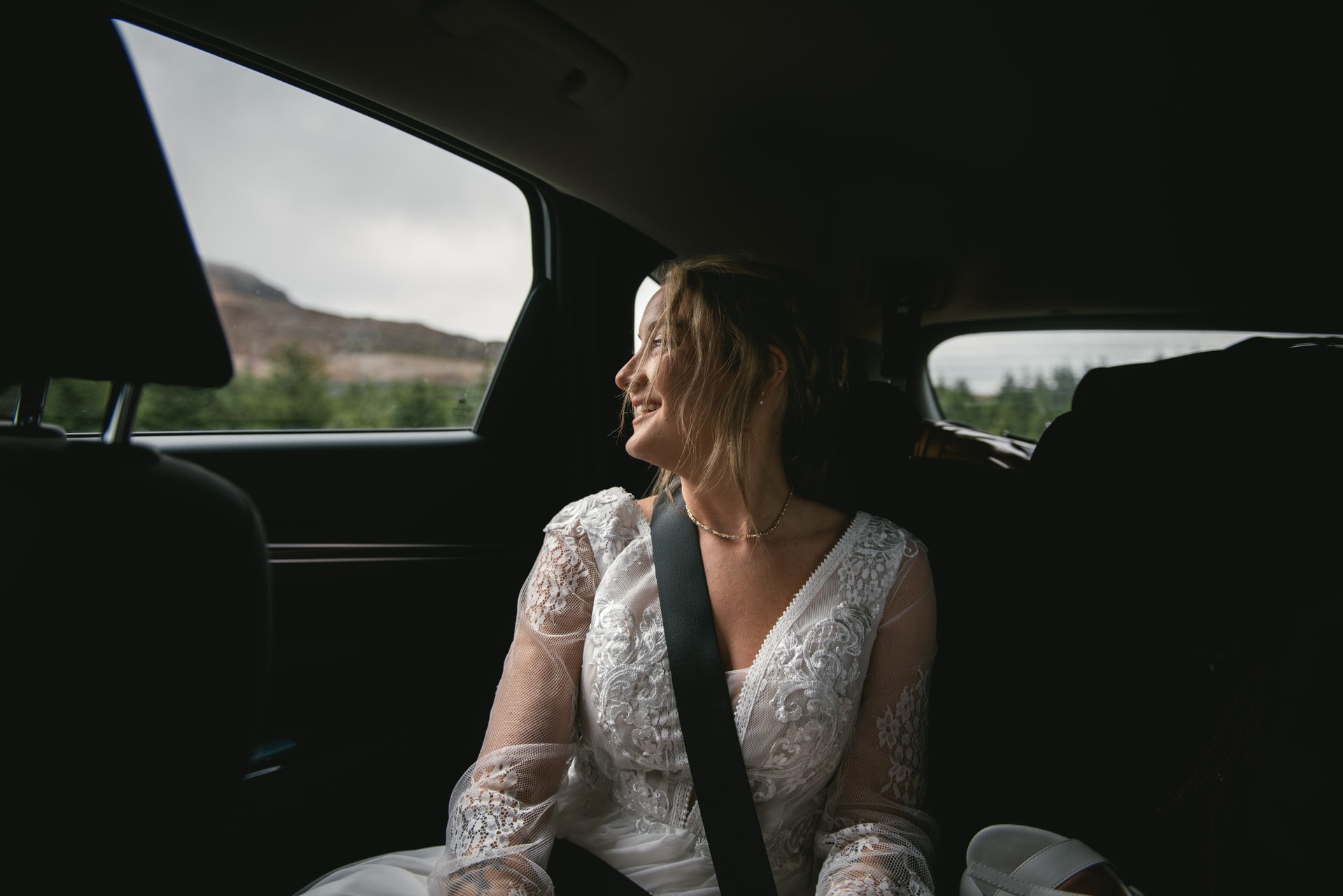 A genuine smile lights up the bride's face as she rides in the car, en route to her Iceland Westfjords elopement destination.