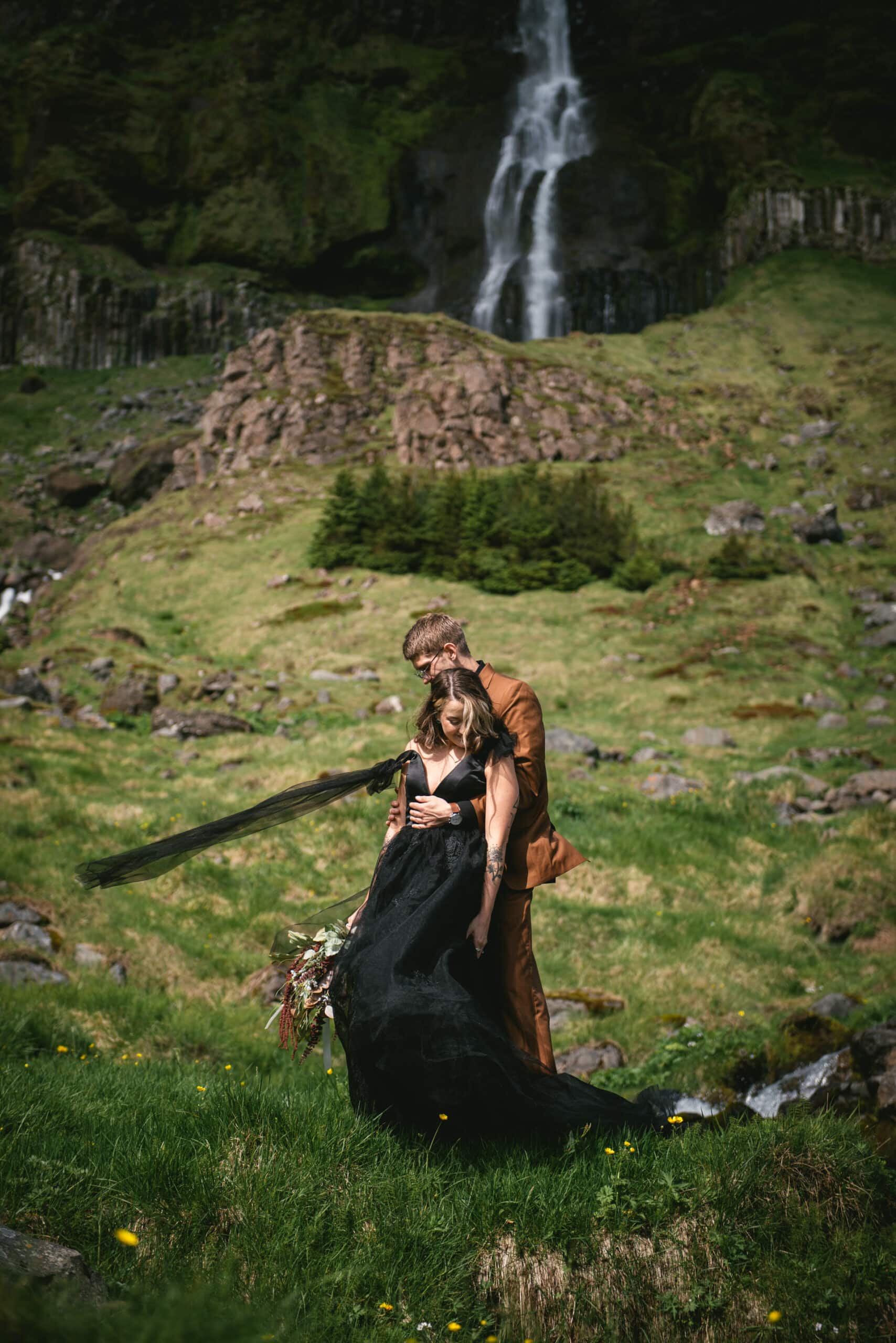 Bride and groom embrace against the backdrop of a tranquil fjord during their Iceland elopement.