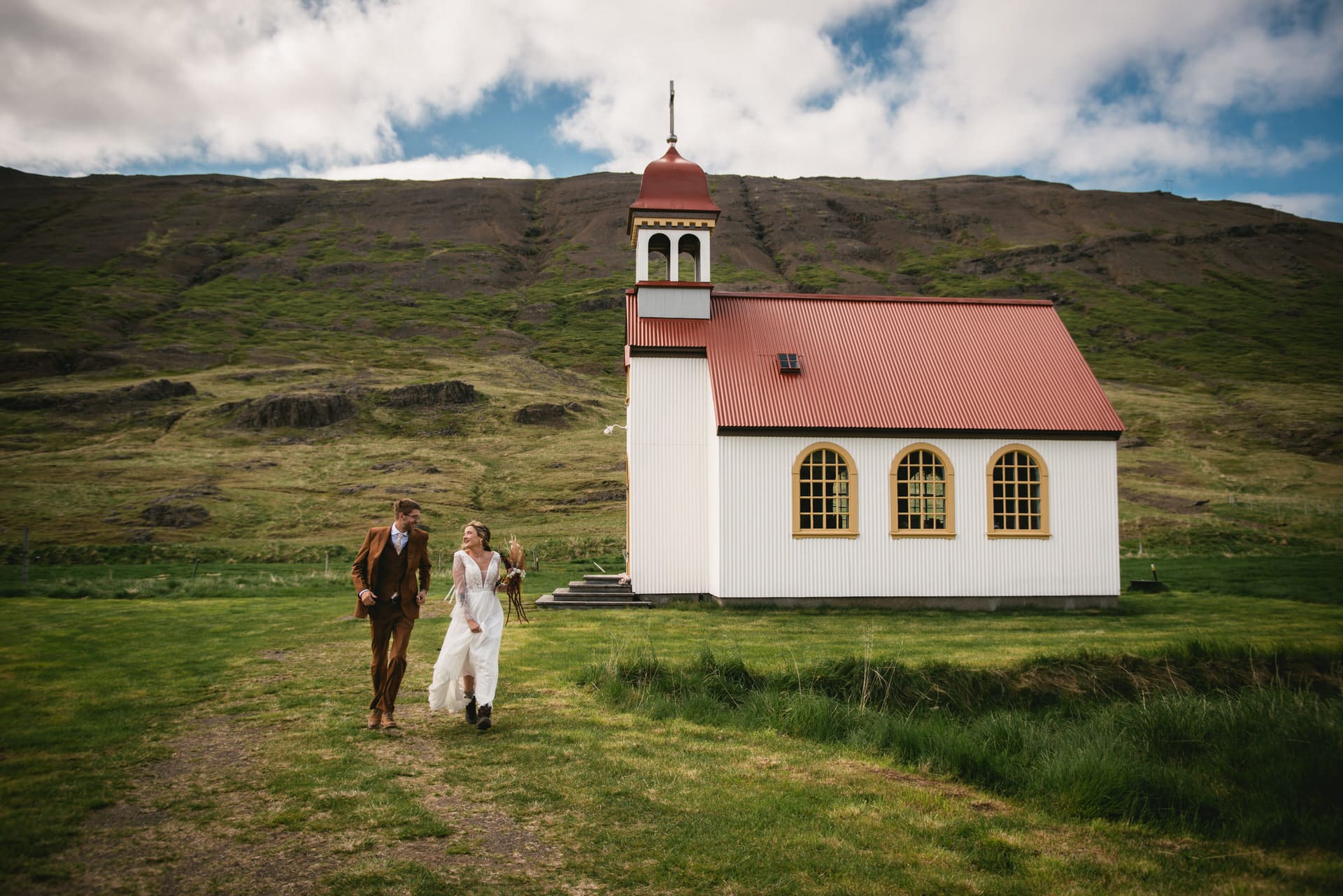 Bride and groom embrace beneath the soft hues of an Icelandic summer sunset.