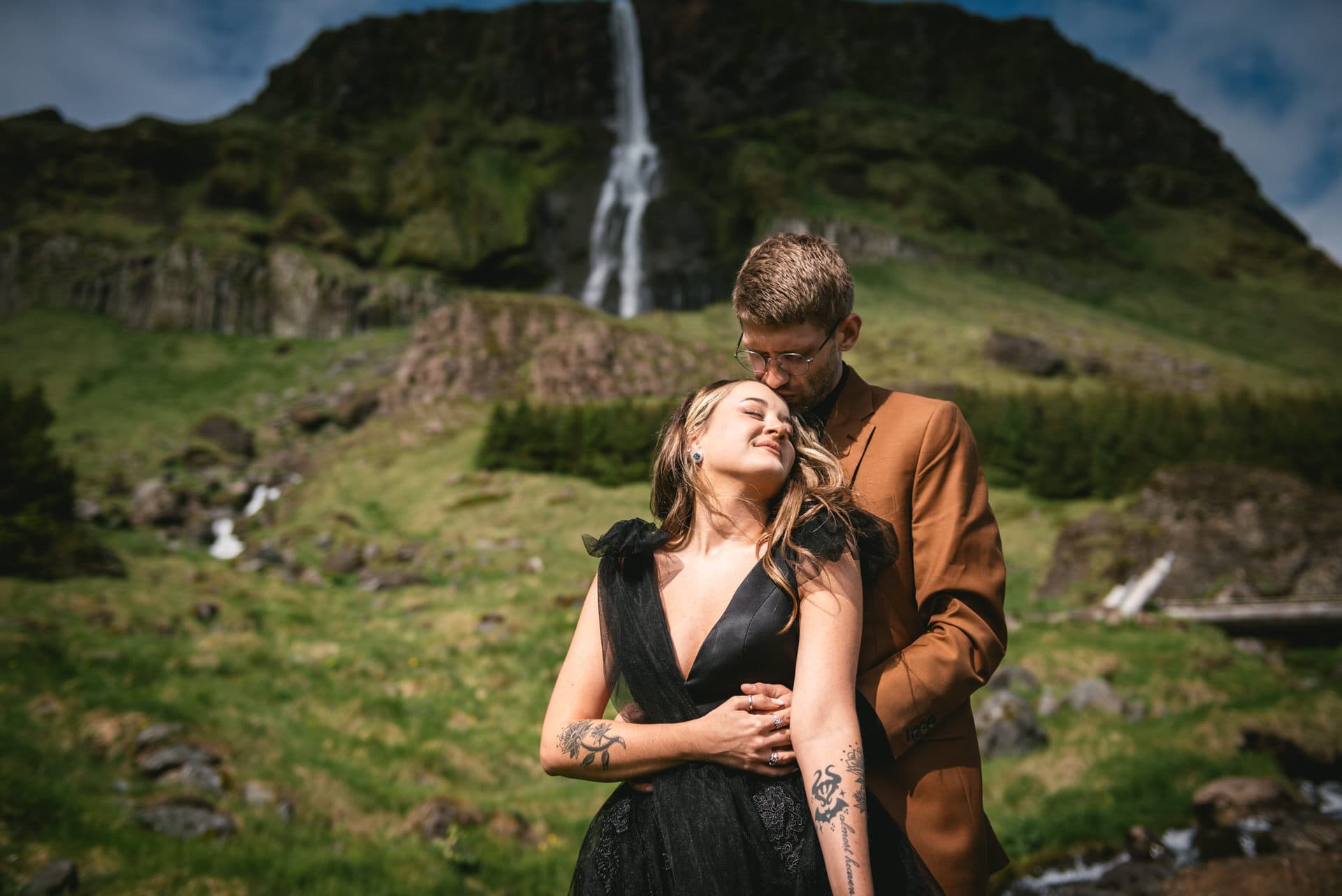 Groom's tender embrace warms the bride against the cool Icelandic breeze.