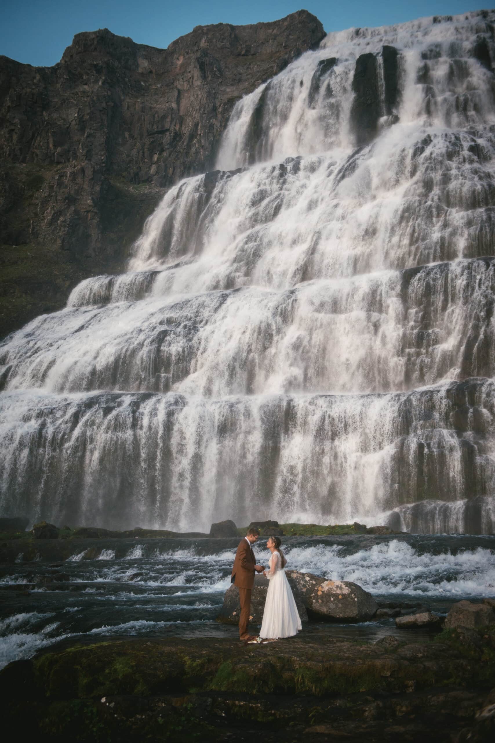 Intimate moment as the couple exchanges vows with a breathtaking waterfall backdrop.