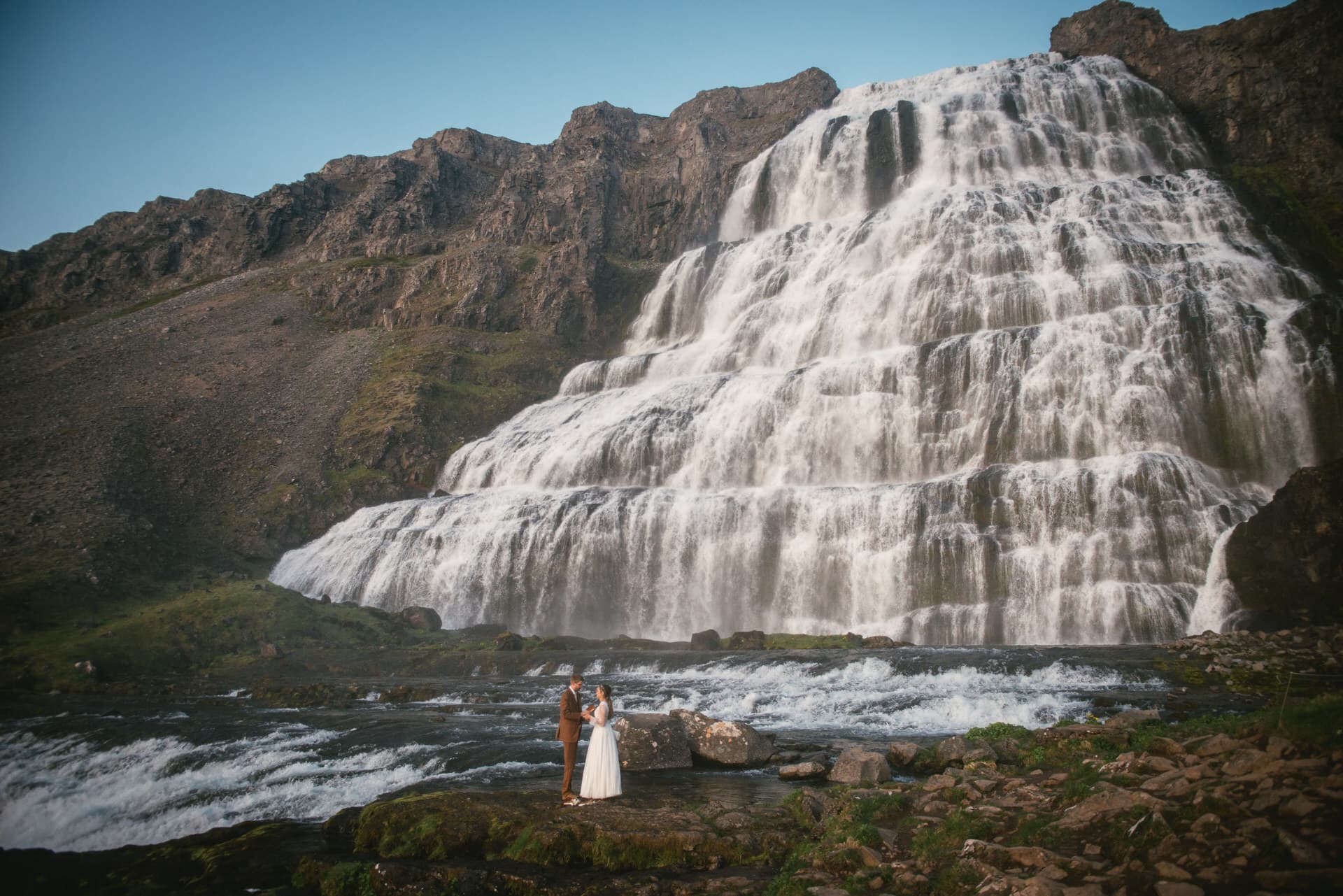 Intimate exchange of vows with a serene fjord and mountainous terrain as witnesses.