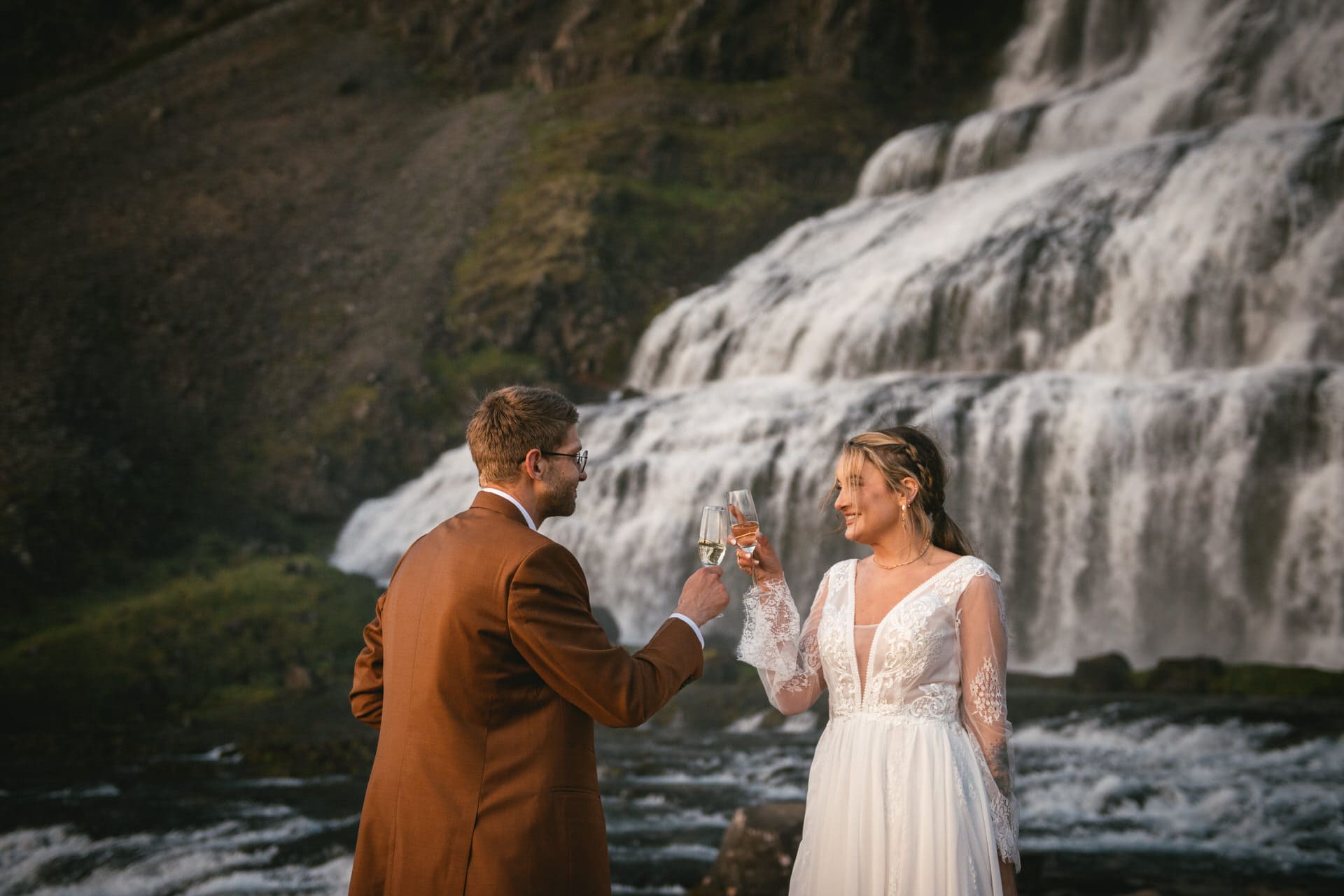 Bride and groom clinking champagne glasses under the midnight sun during their Iceland elopement.