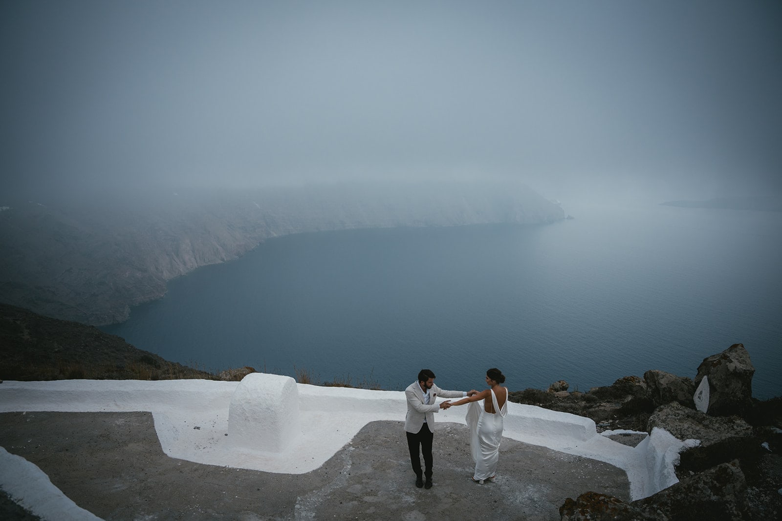 Couple doing their first dance at blue hour on Santorini with Fira in the background