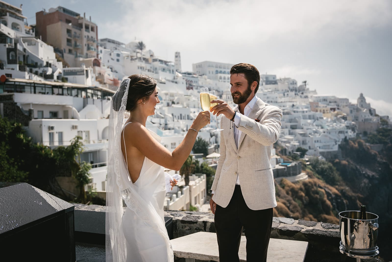 Champagne toasts by the pool, celebrating the start of their forever in Fira’s embrace