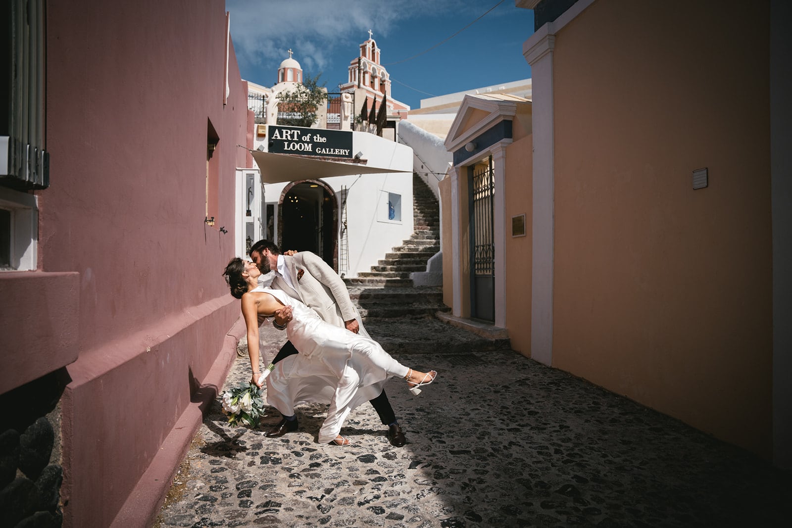 Their shadows mingling on cobblestones, a quiet testament to their elopement on Santorini