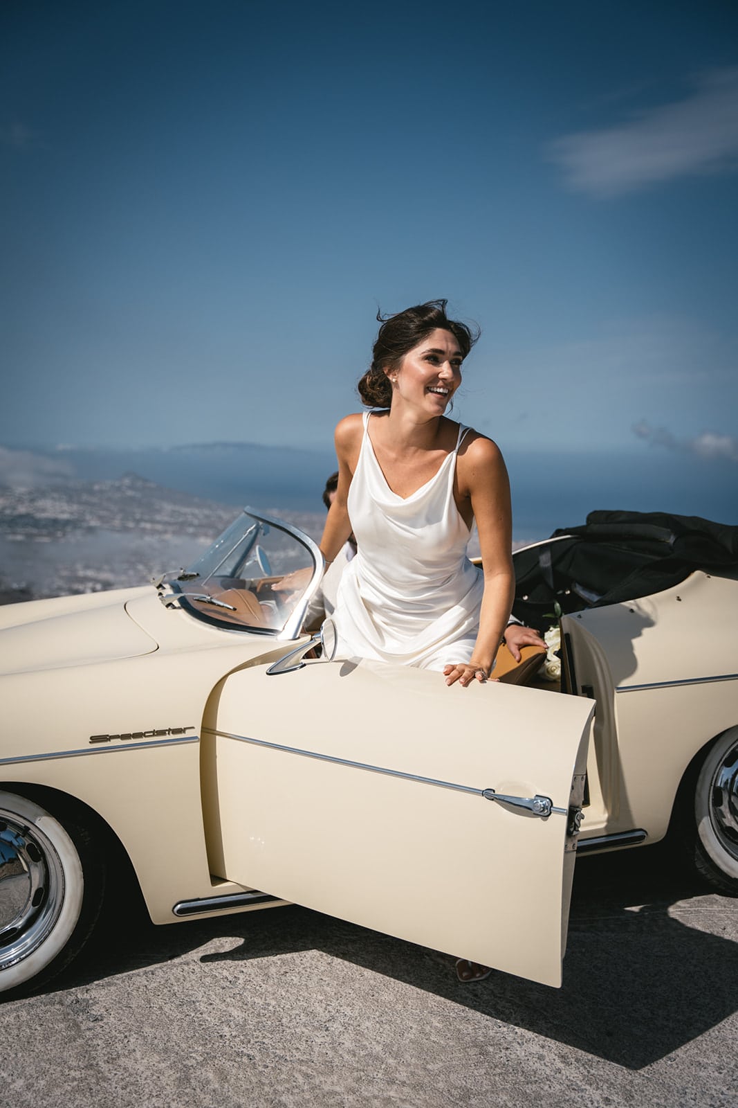 Elopement dreams elevate, with the couple and their vintage car framed by the sky