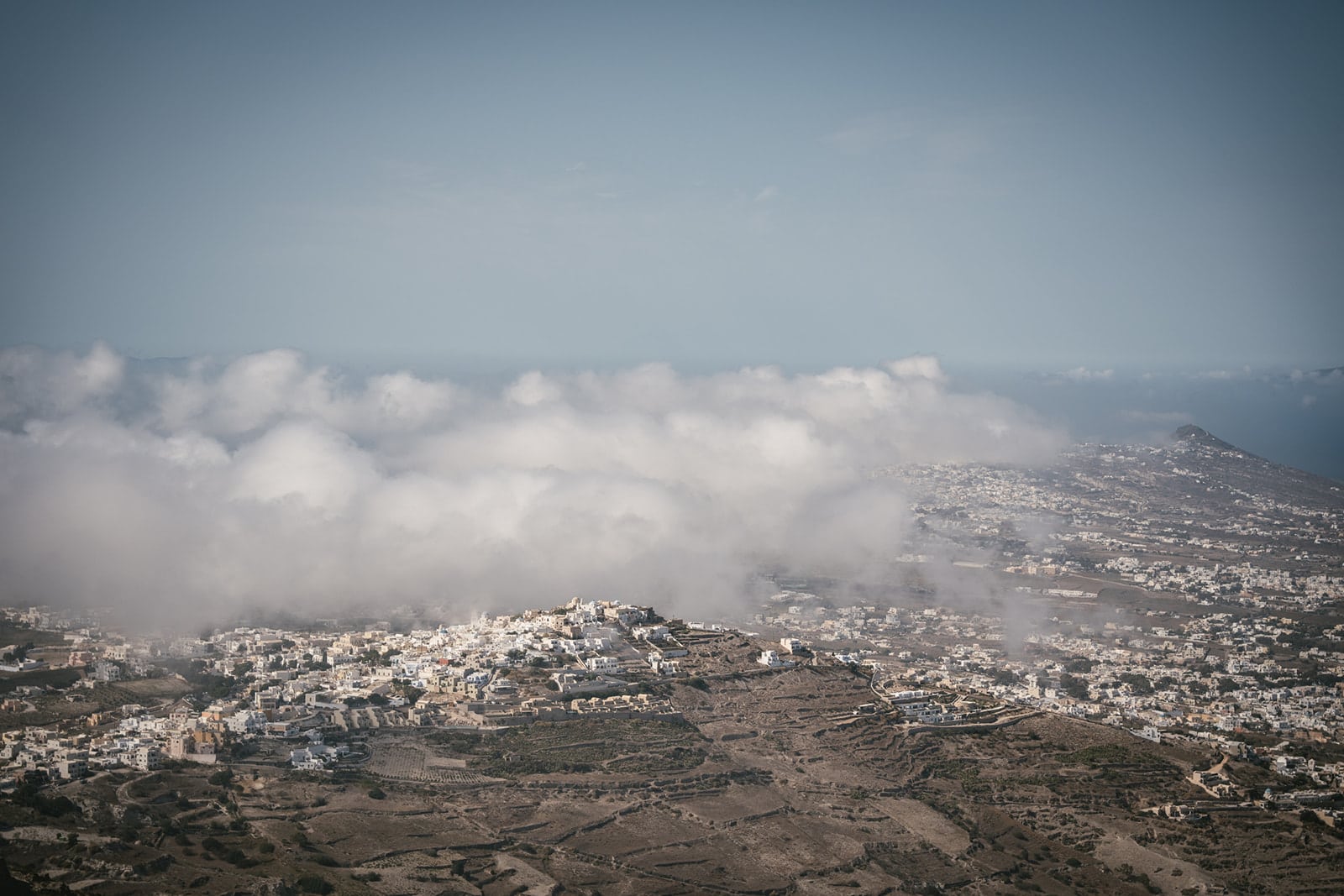 Santorini spreads below, a breathtaking backdrop to their elopement dreams