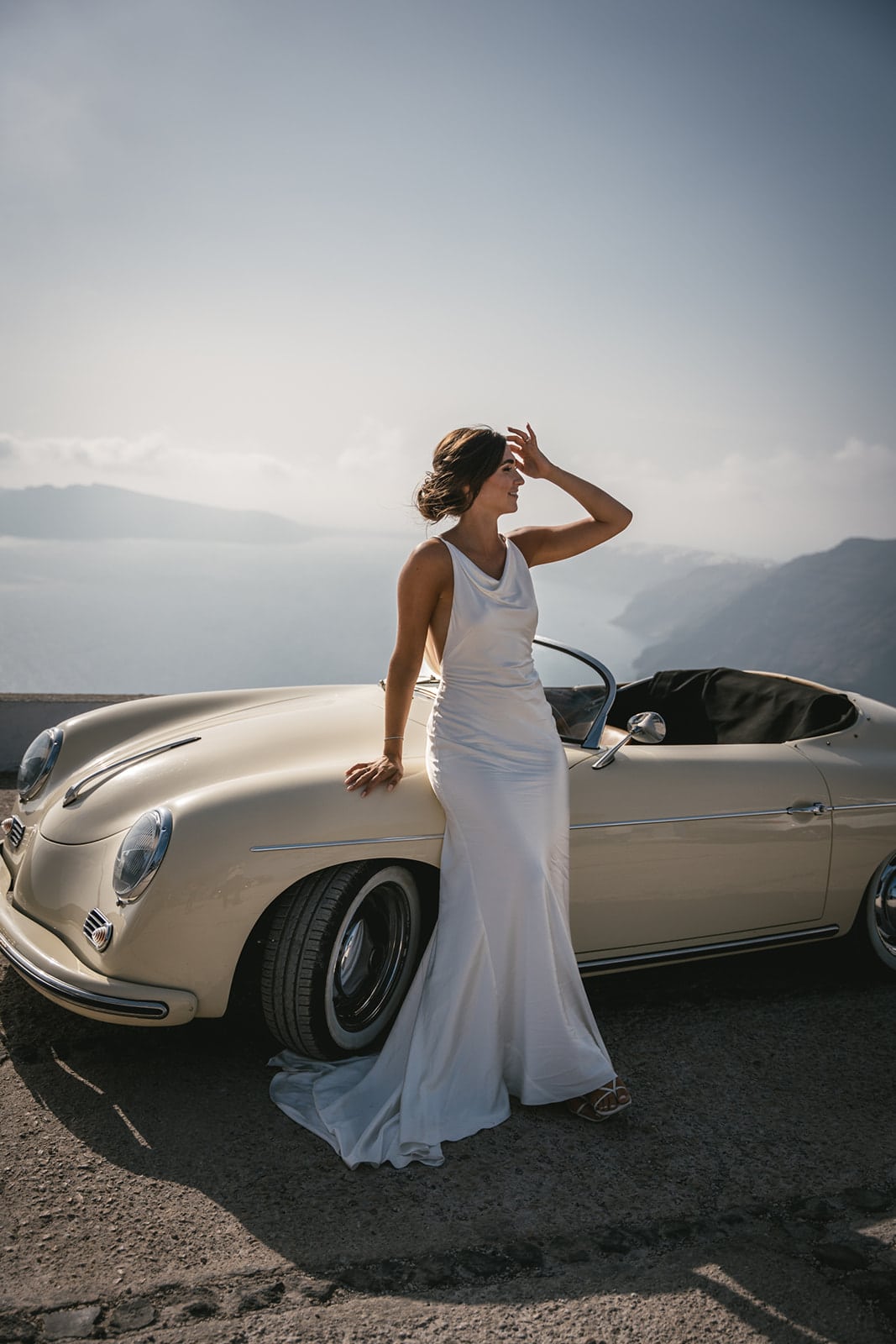 Beneath Santorini’s sky, by the sea, their vintage car awaits to whisk them to forever