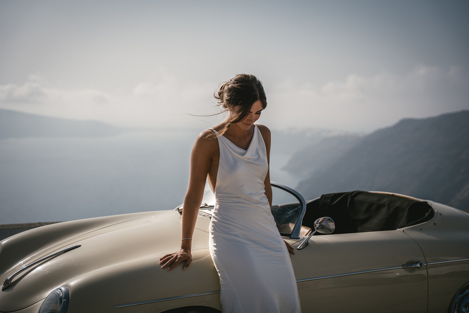 As the waves dance behind, their love story unfolds in the embrace of the vintage car