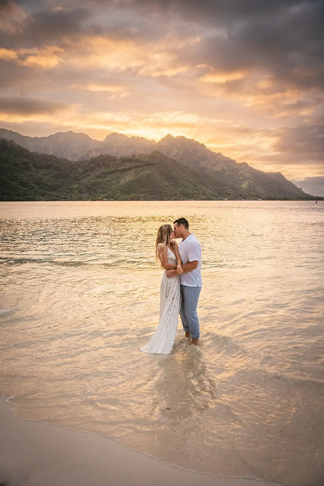 Groom lifting the bride in joy on a sunlit Polynesian beach
