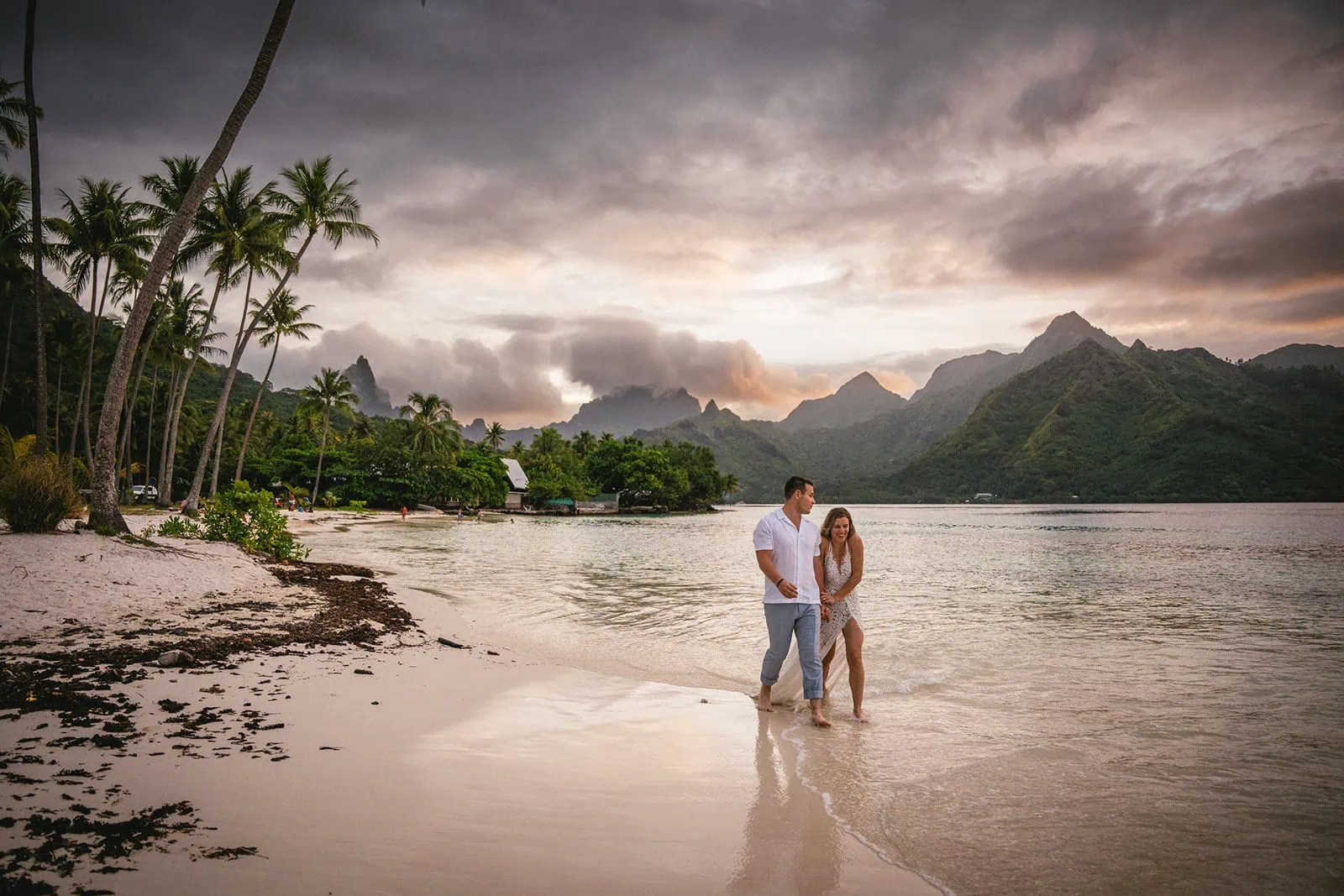 Newlyweds enjoying a sunset walk on the beach, leaving footprints in the sand
