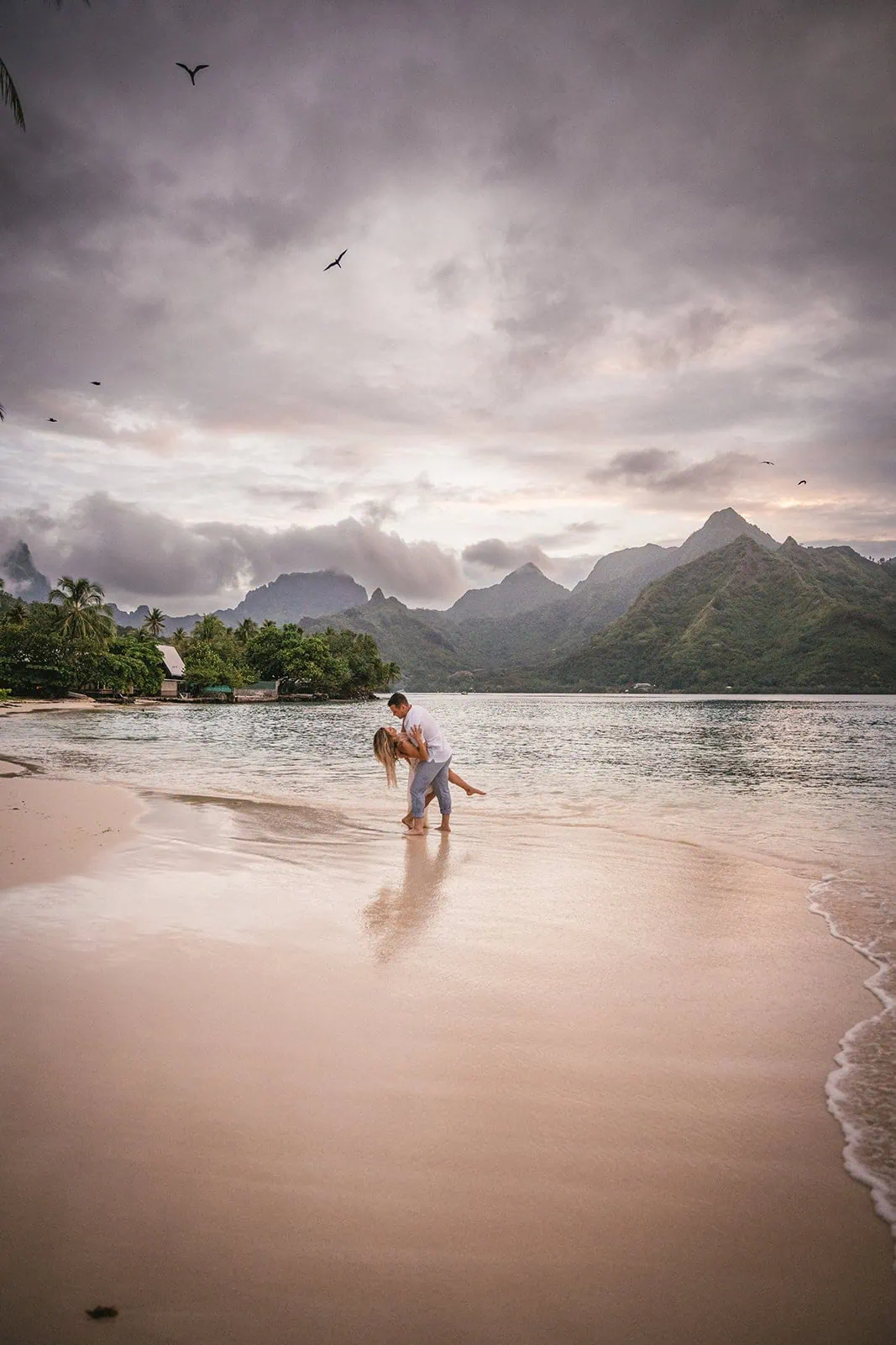Newlyweds sharing a playful moment on a French Polynesia beach swing