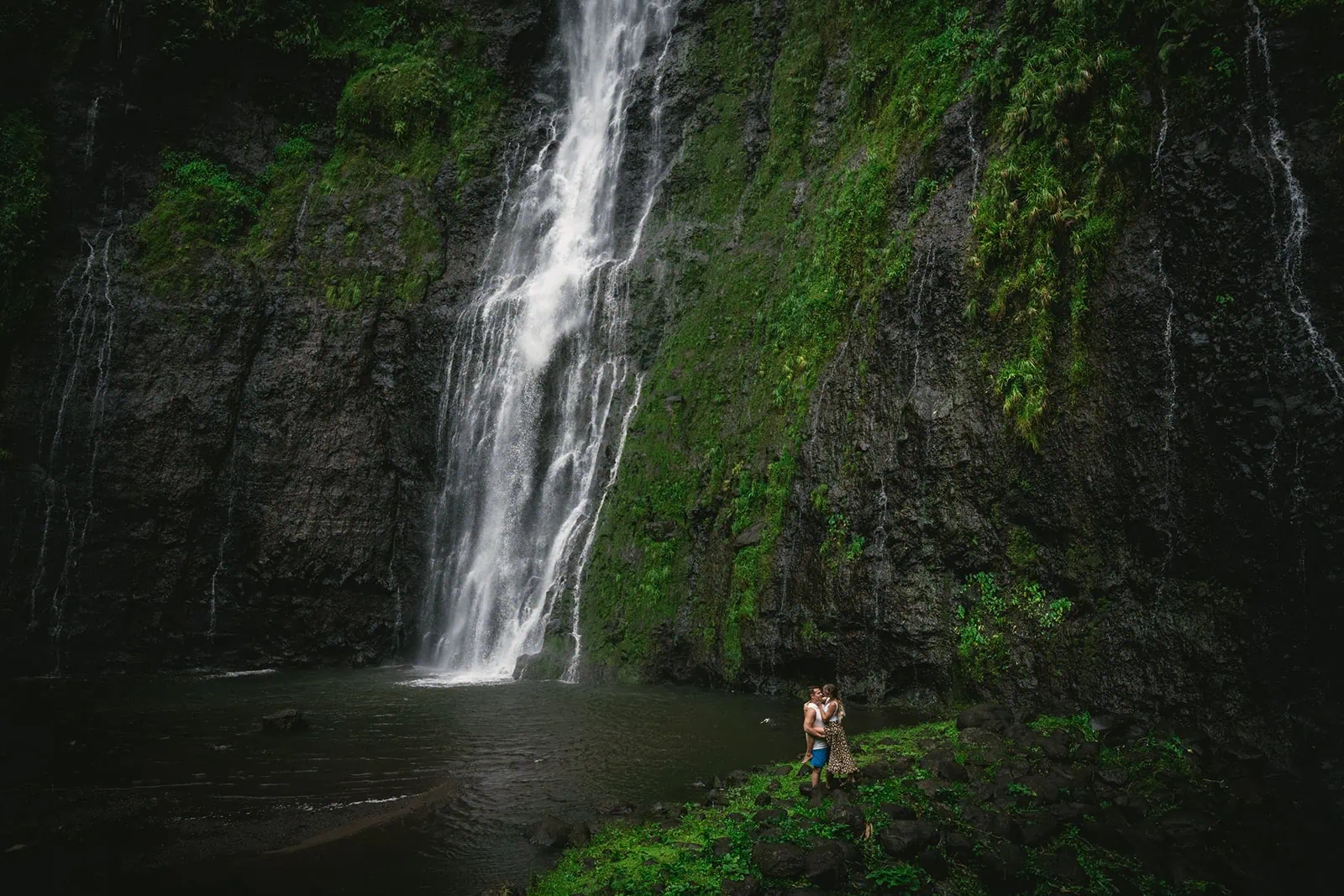 Bride and groom embracing, with a backdrop of vibrant Polynesian flora