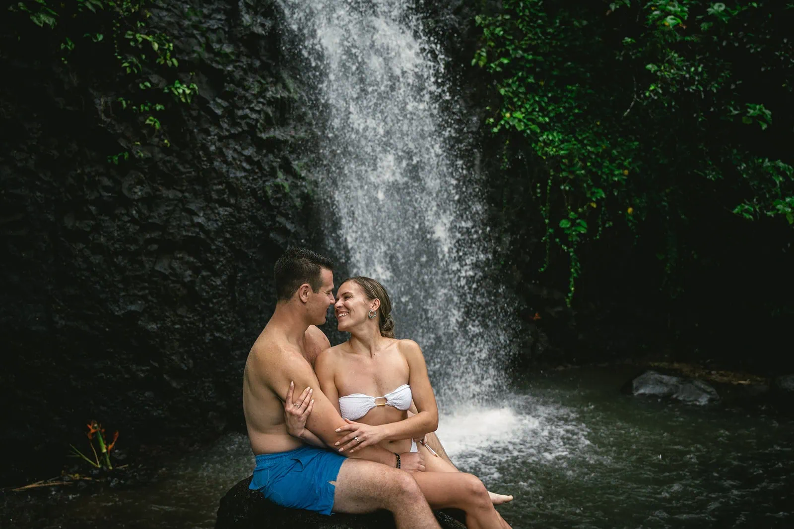 Newlyweds taking a romantic stroll through a Polynesian waterfall