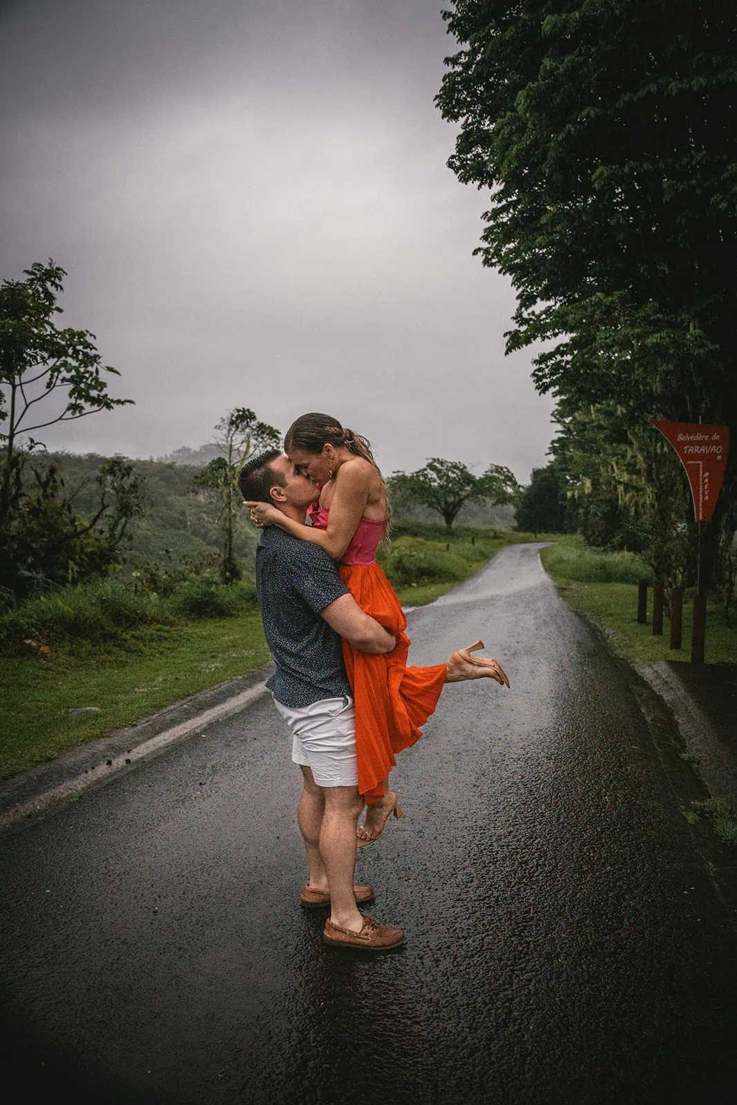 Newlyweds kissing in the rain, adding a magical touch to their French Polynesia elopement
