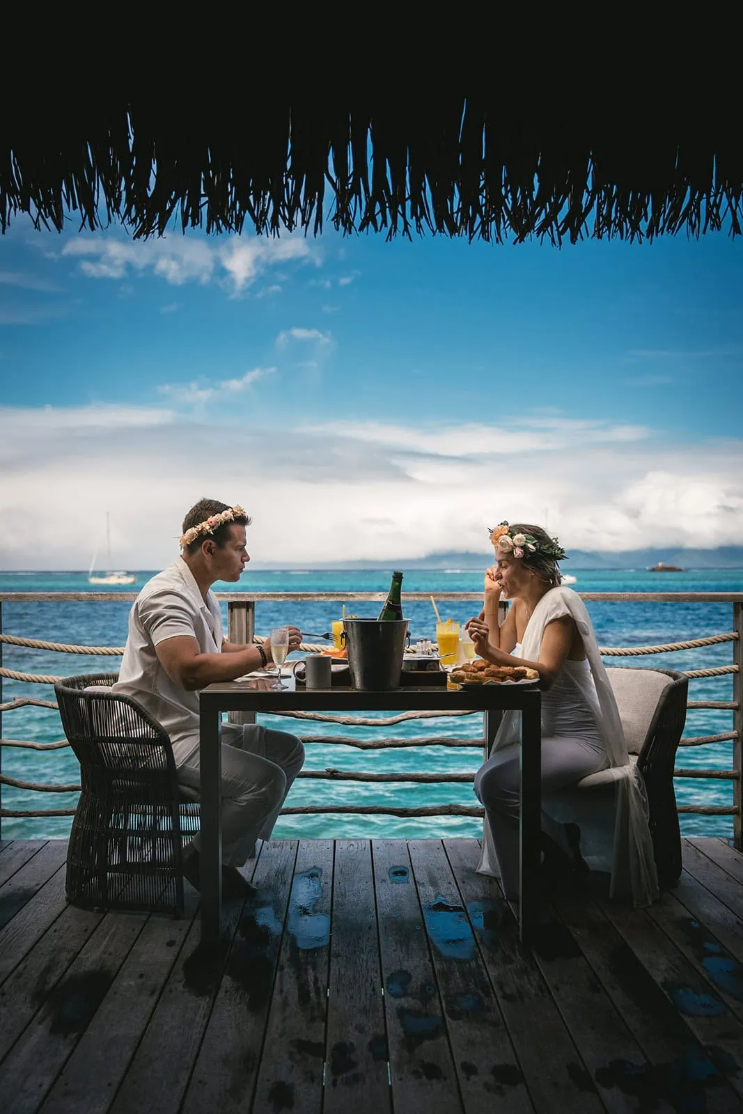 Newlyweds enjoying a relaxing meal by the sea in French Polynesia.