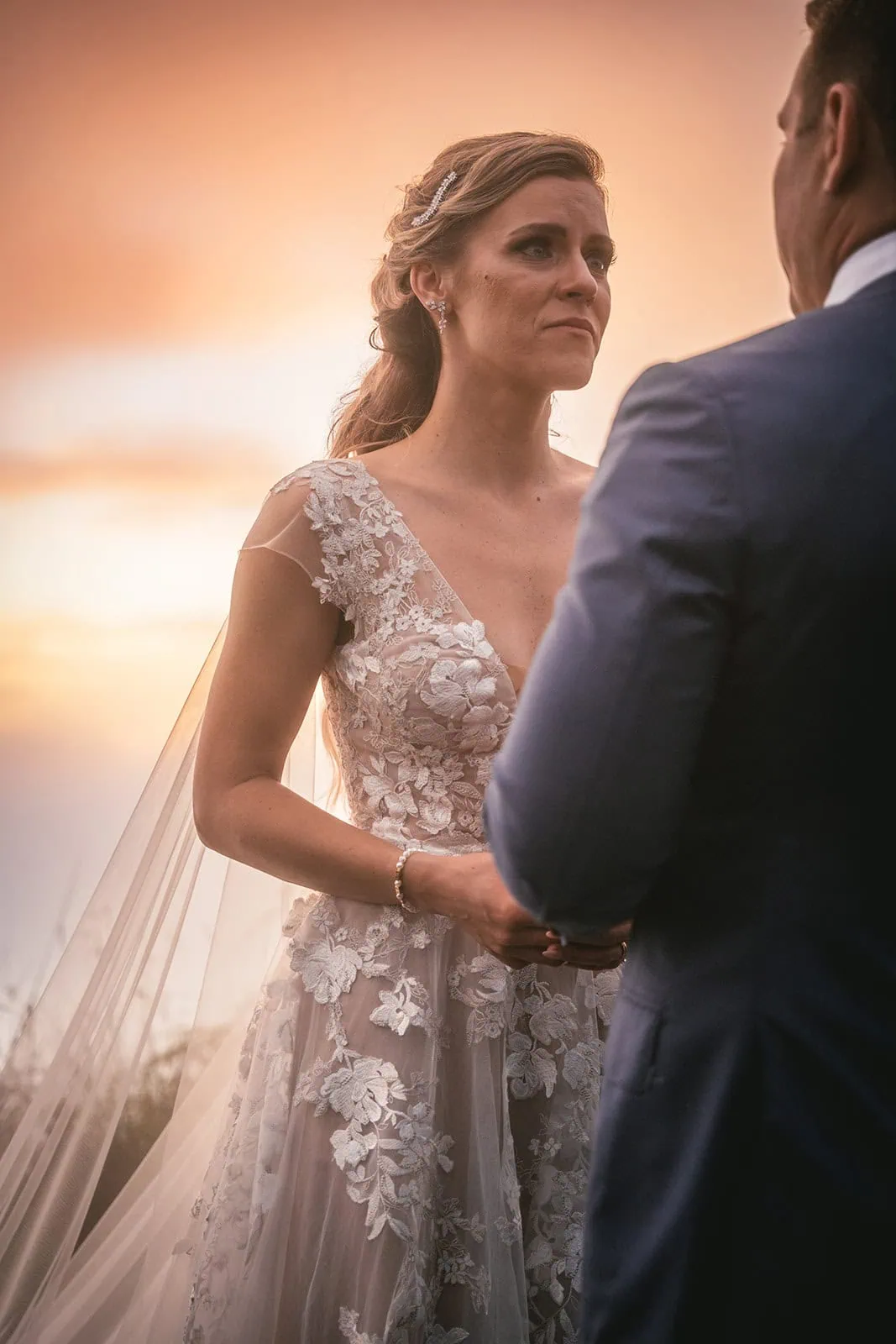 Couple exchanging vows with dramatic mountain views in the background, under the sunset of French Polynesia