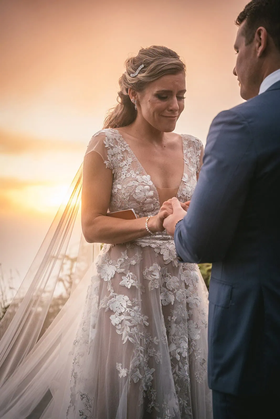 Groom placing the ring on the bride’s finger, with the sunset as a backdrop in French Polynesia