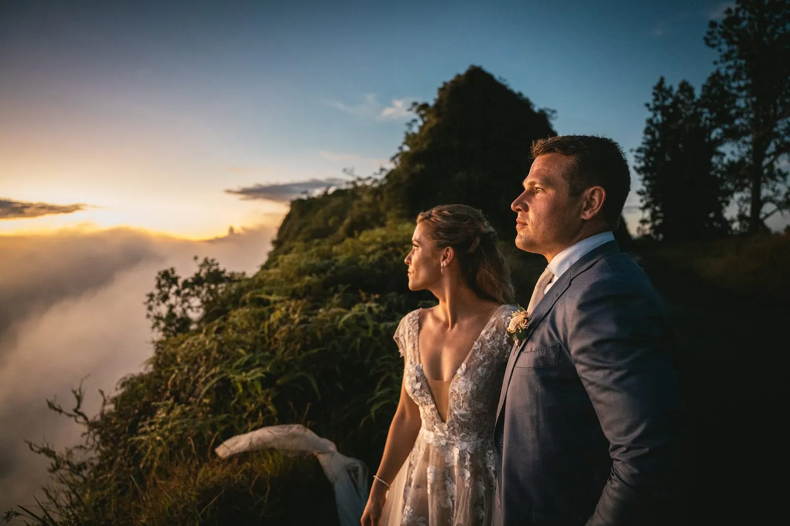 Dramatic shot of the bride and groom against a backdrop of towering Polynesian cliffs