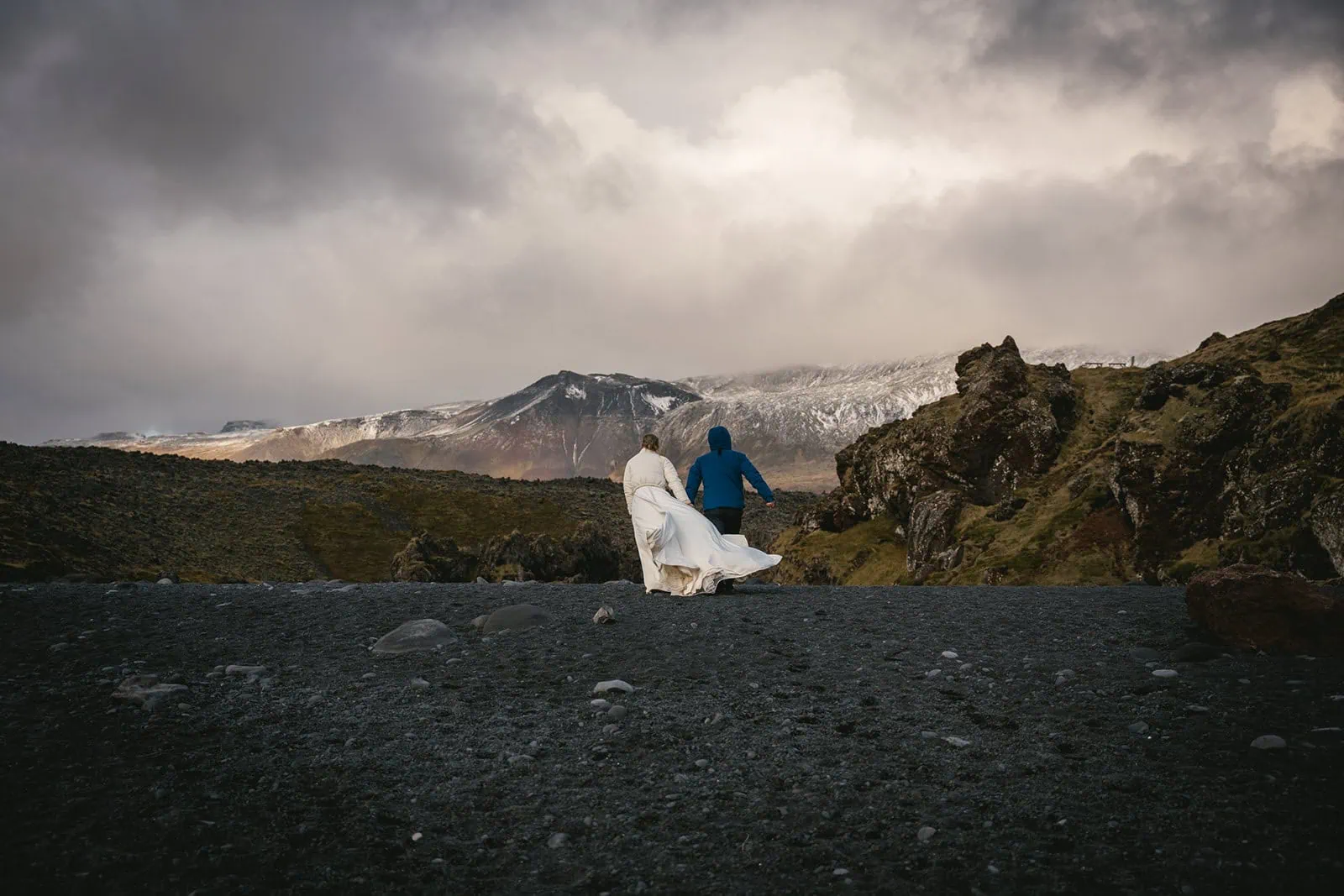 Iceland elopement: Newlyweds walking hand in hand on a black sand beach