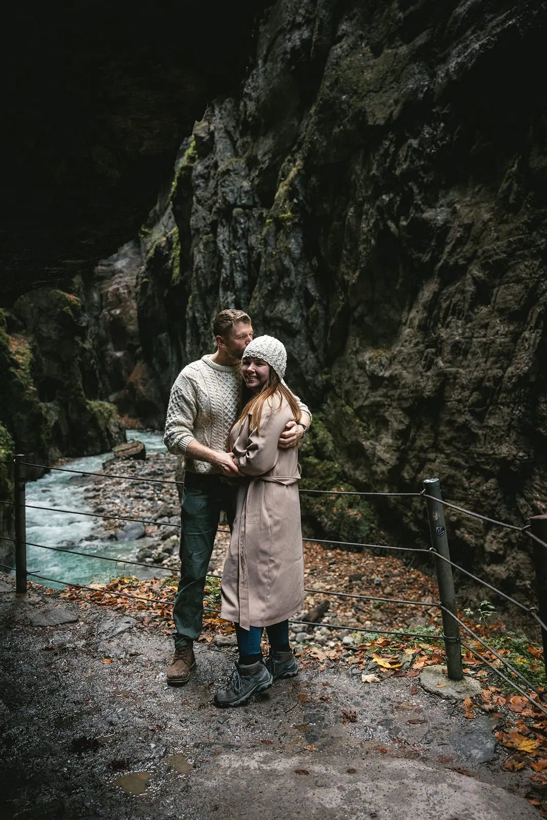Elopement photo of newlyweds framed by the dramatic entrance of a German cave, showcasing the rugged beauty of their adventure
