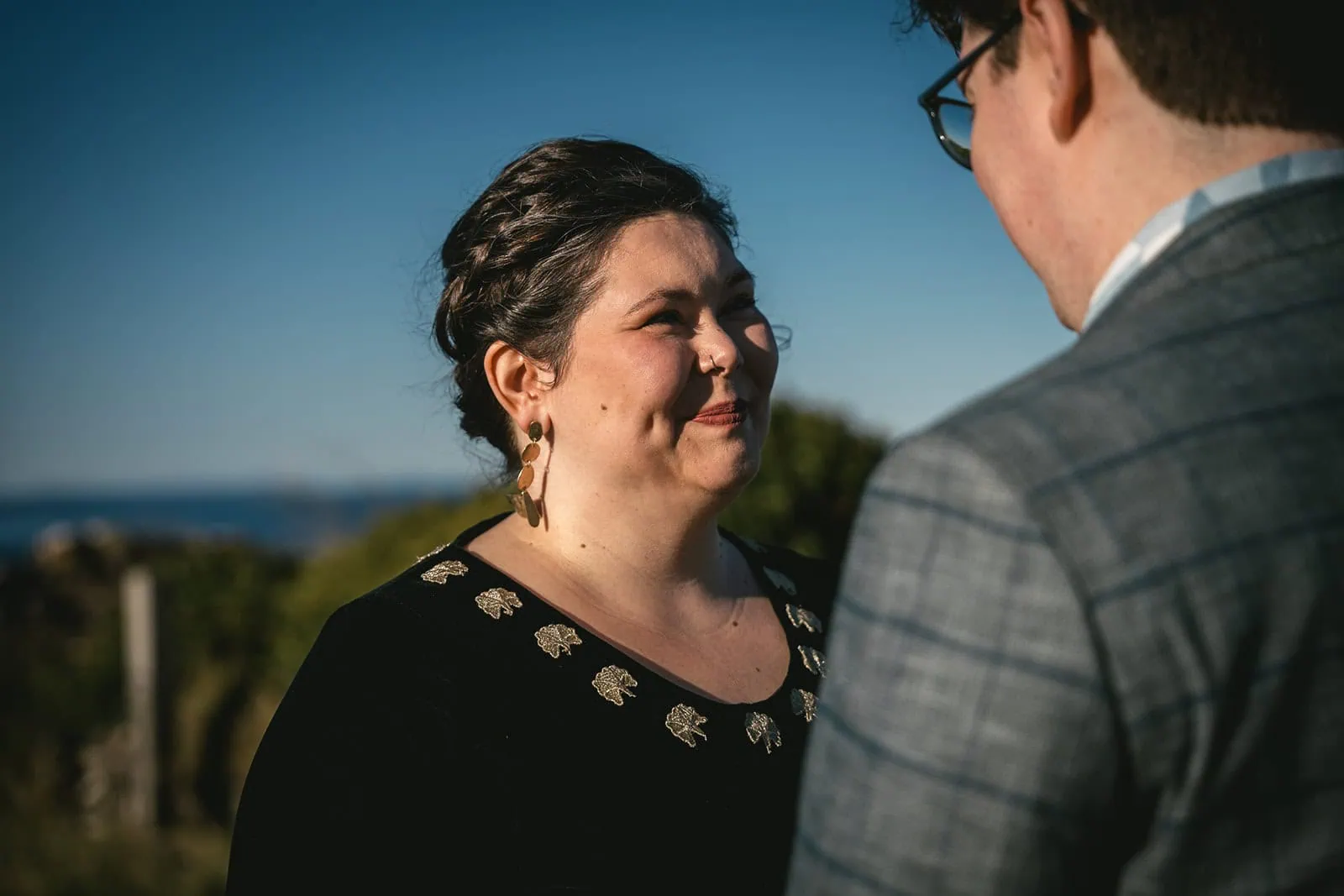 Bride smiling broadly as she looks at the groom, with the serene landscape during their Scotland elopement in the Isle of Skye