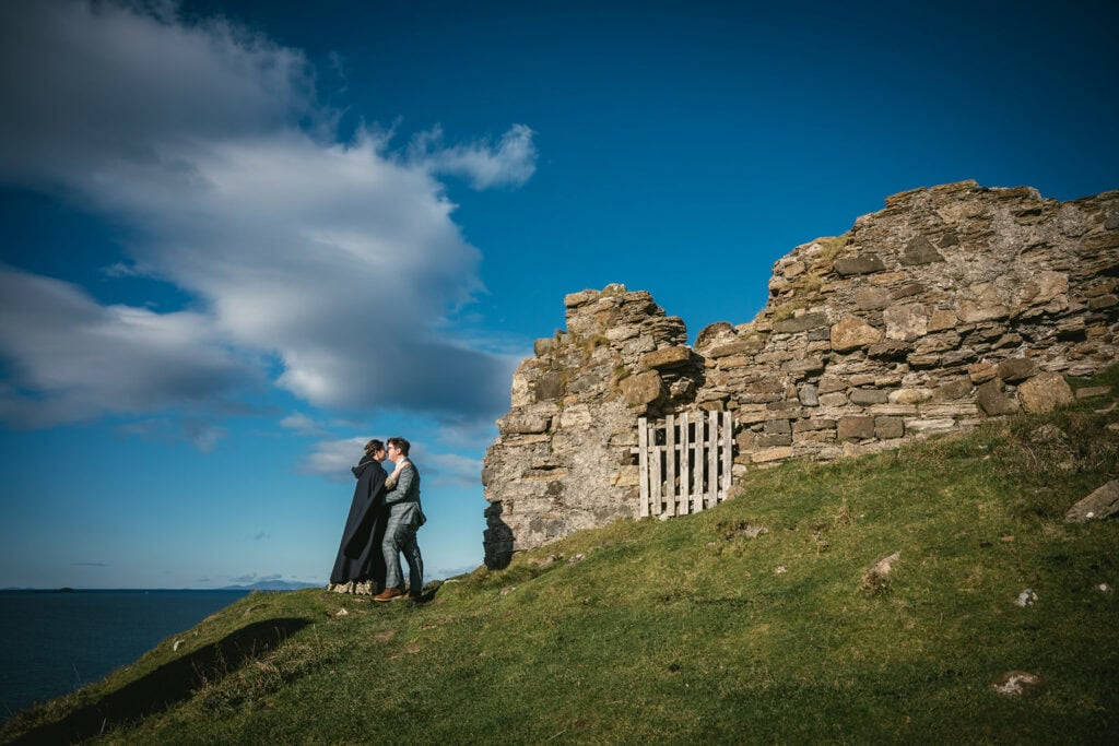 Newlyweds standing by a Scottish castle in ruins during their Skye elopement