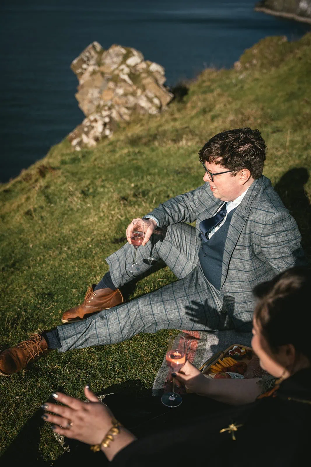 Bride and groom sitting close together on a rocky Skye shore