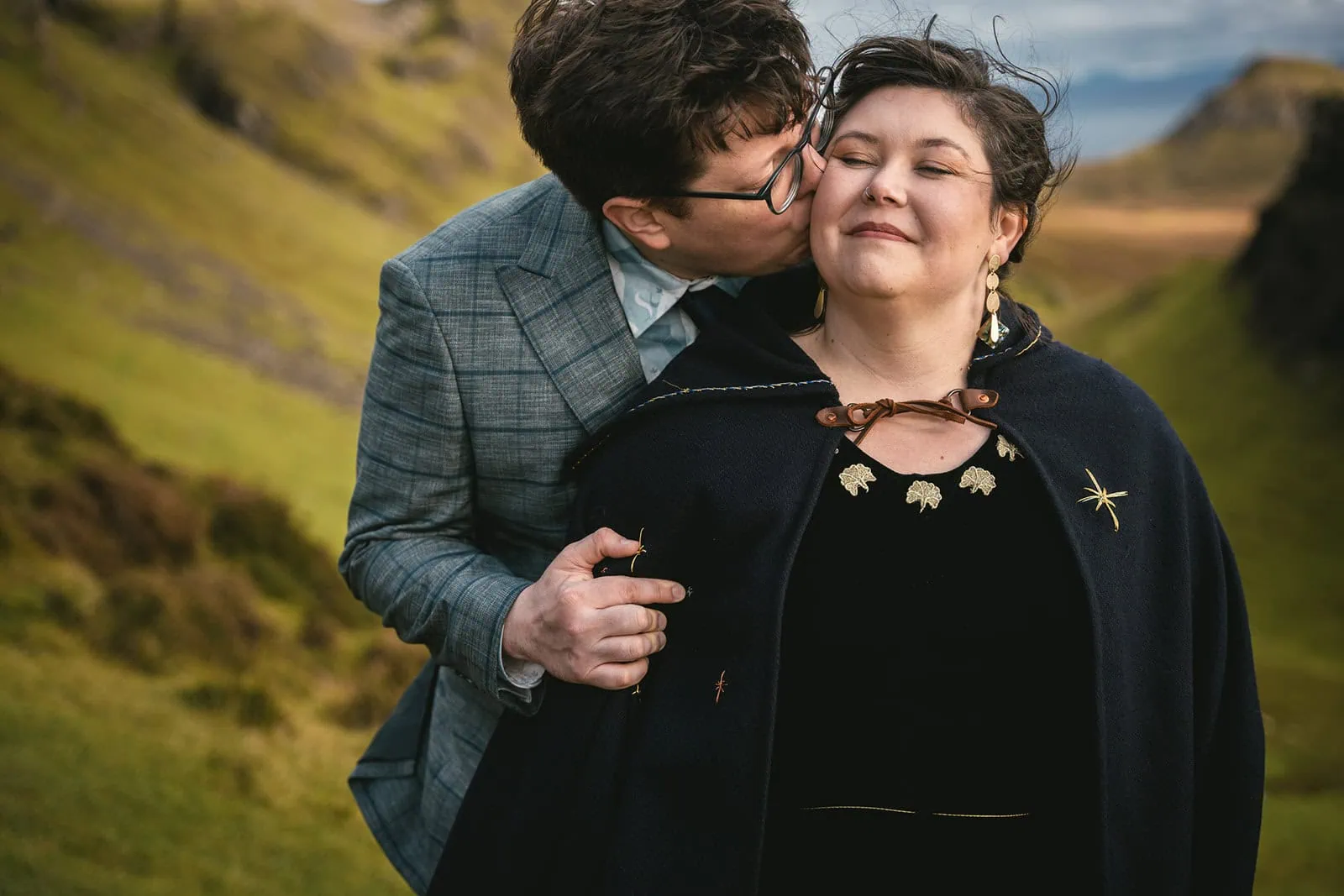 Newlyweds kissing on a hill overlooking the lush Skye landscape, celebrating their Scotland elopement