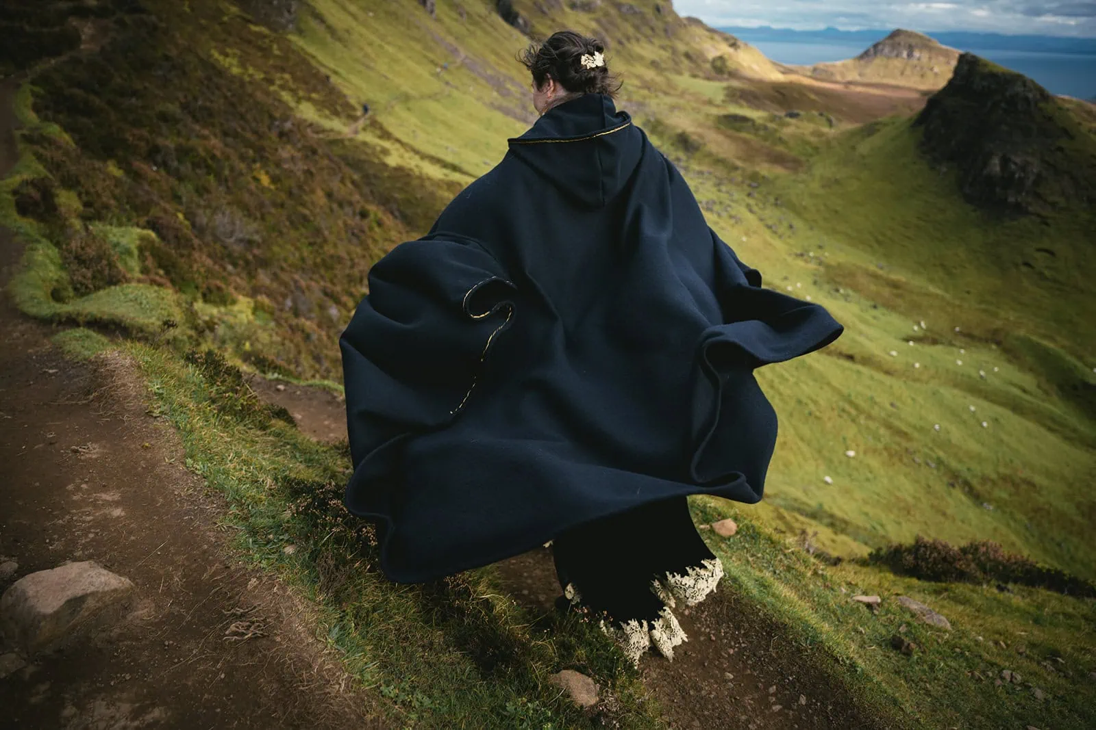 Bride's flowing cape caught in the Skye wind, adding drama to her Scotland elopement