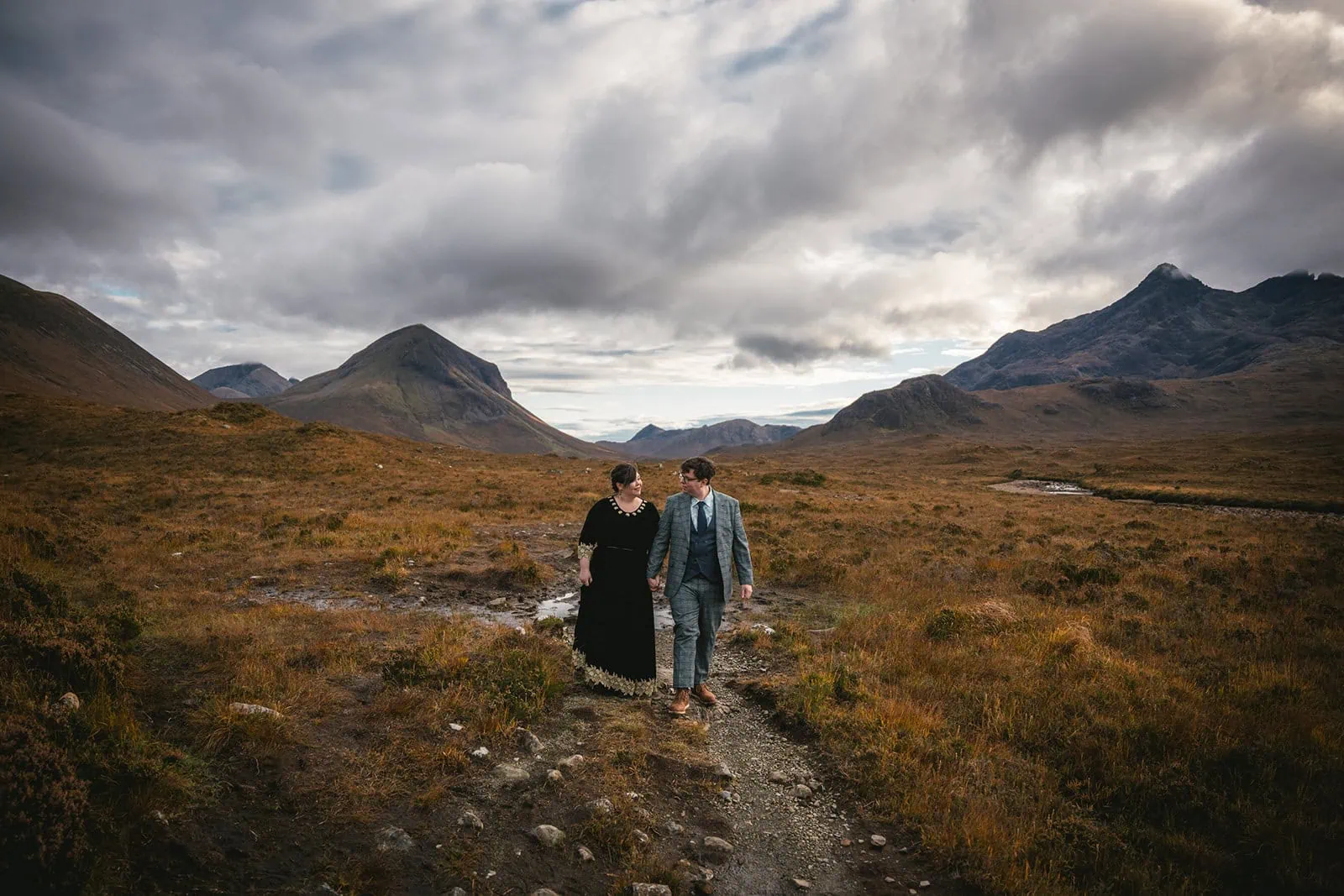 Newlyweds walking through a rugged terrain in their Skye elopement