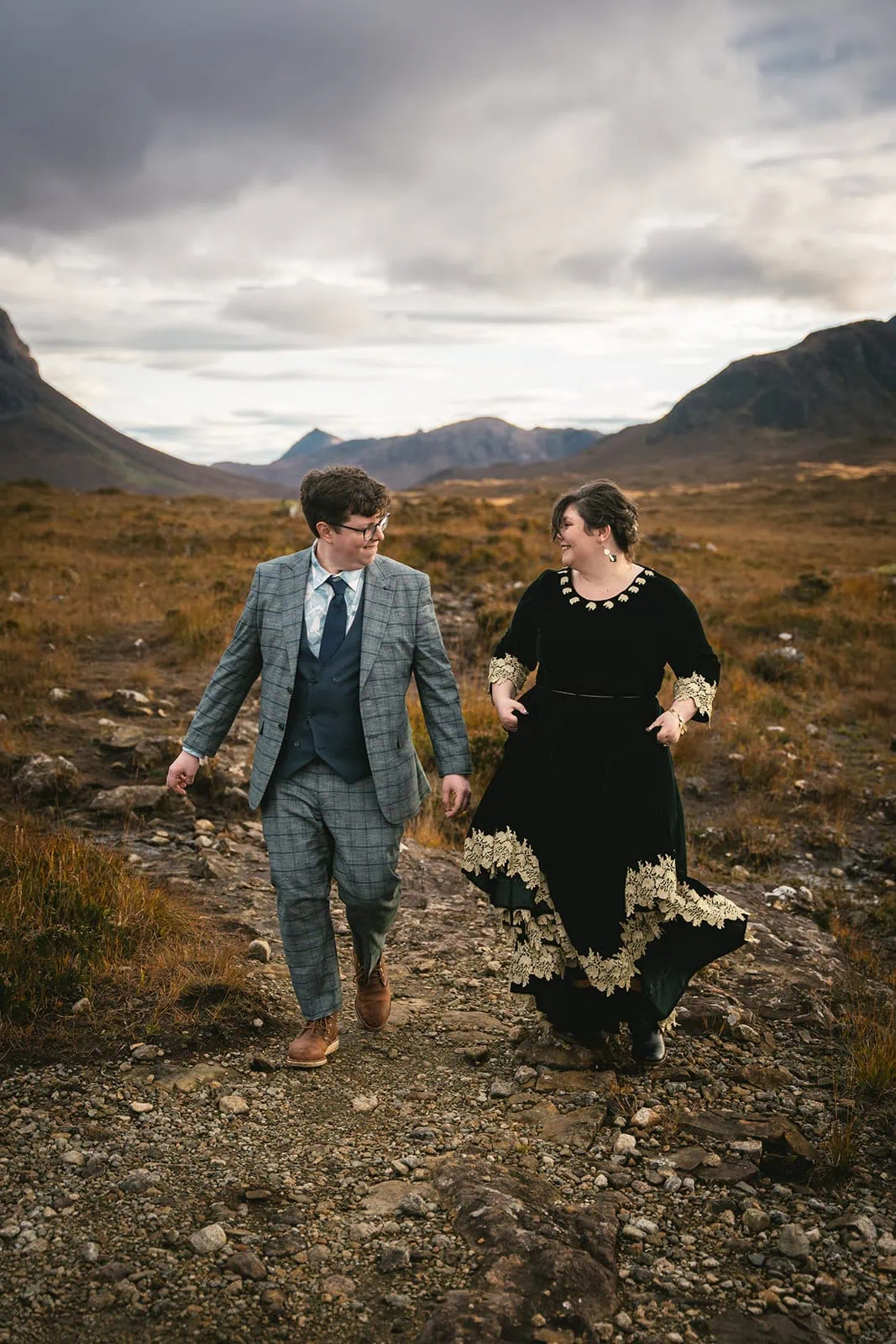 Bride and groom posing with the rugged terrain of Skye in the background