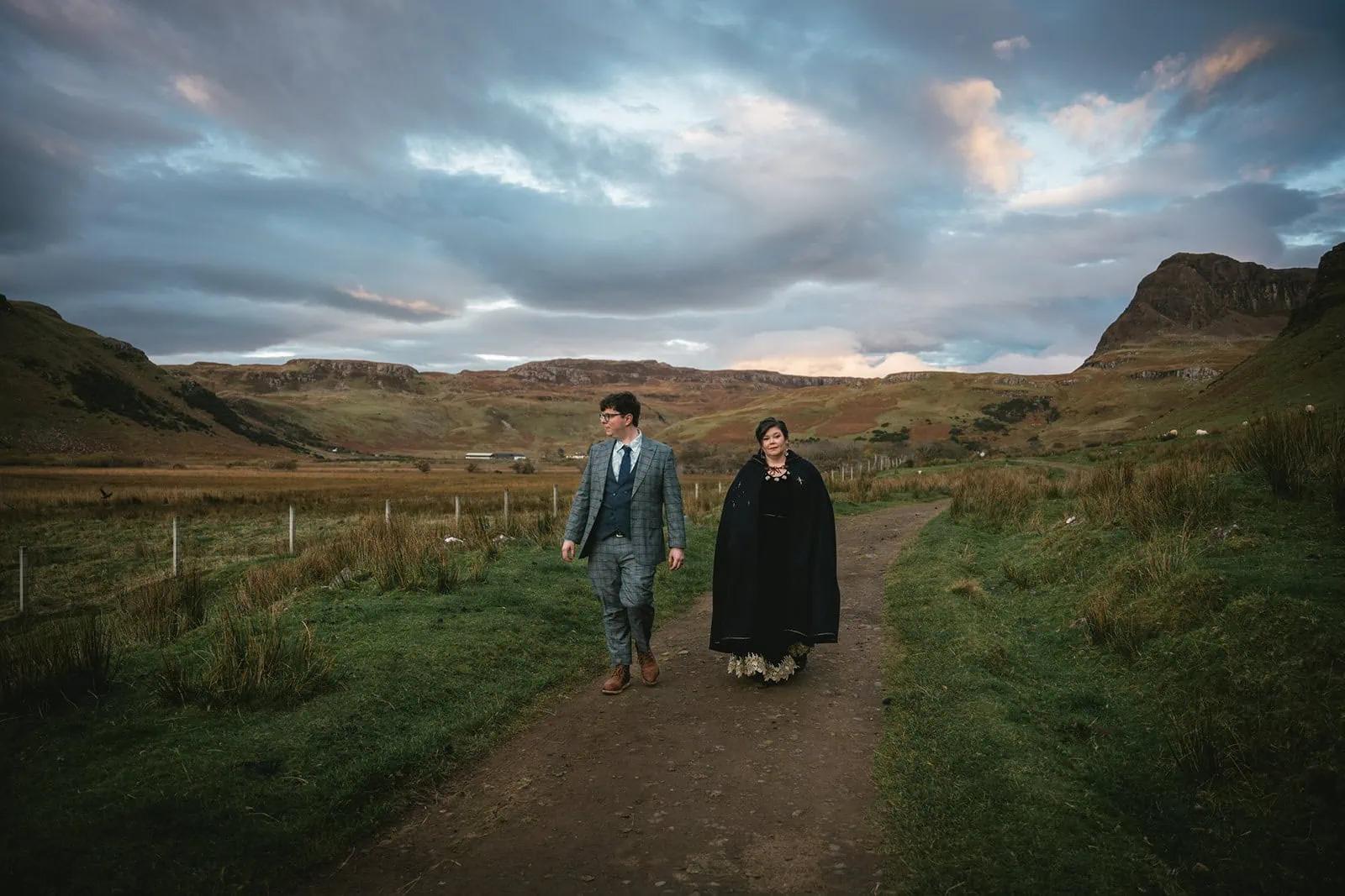 Newlyweds walking along a secluded path at sunset in their Skye elopement