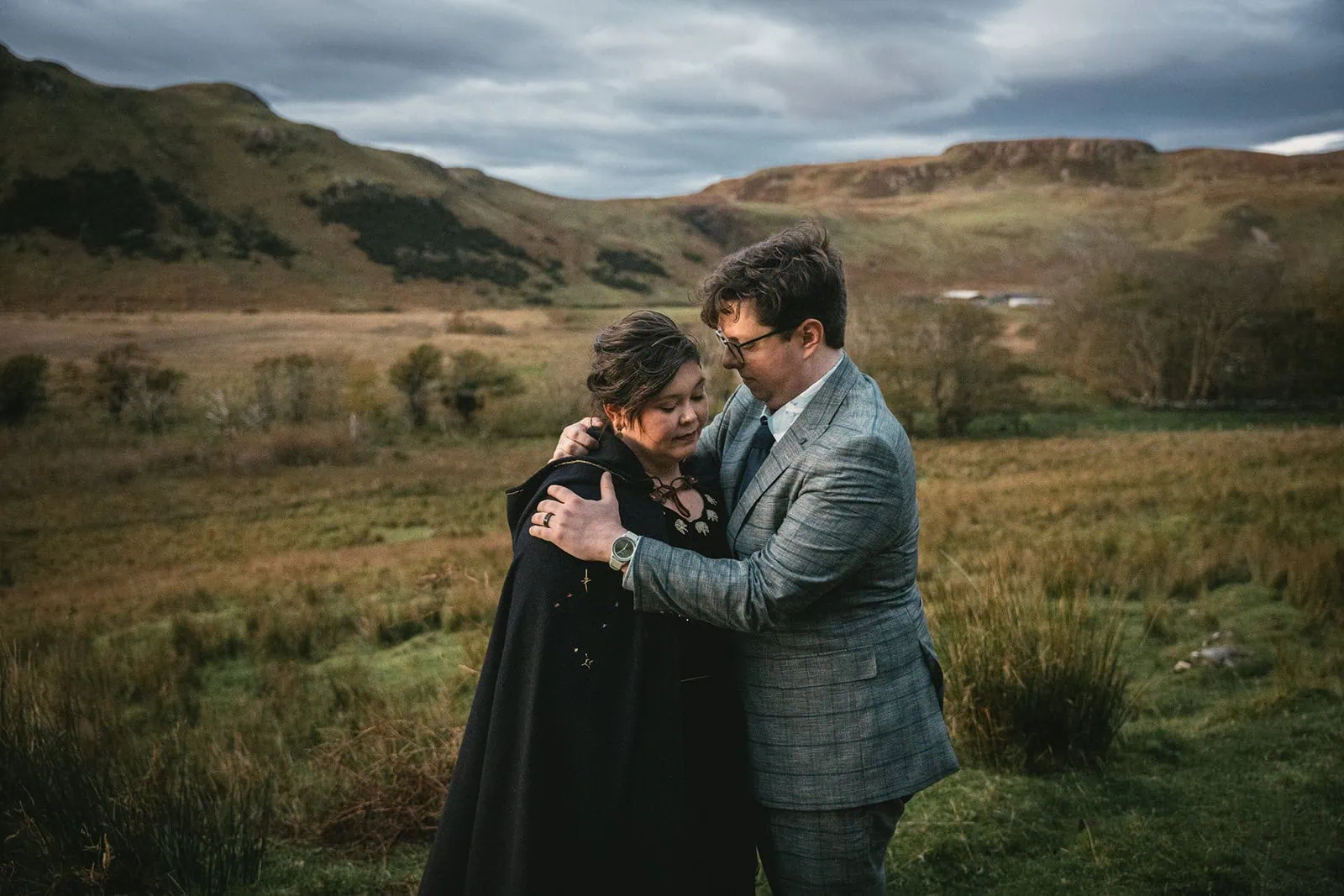 Groom whispering in the bride’s ear, both smiling widely