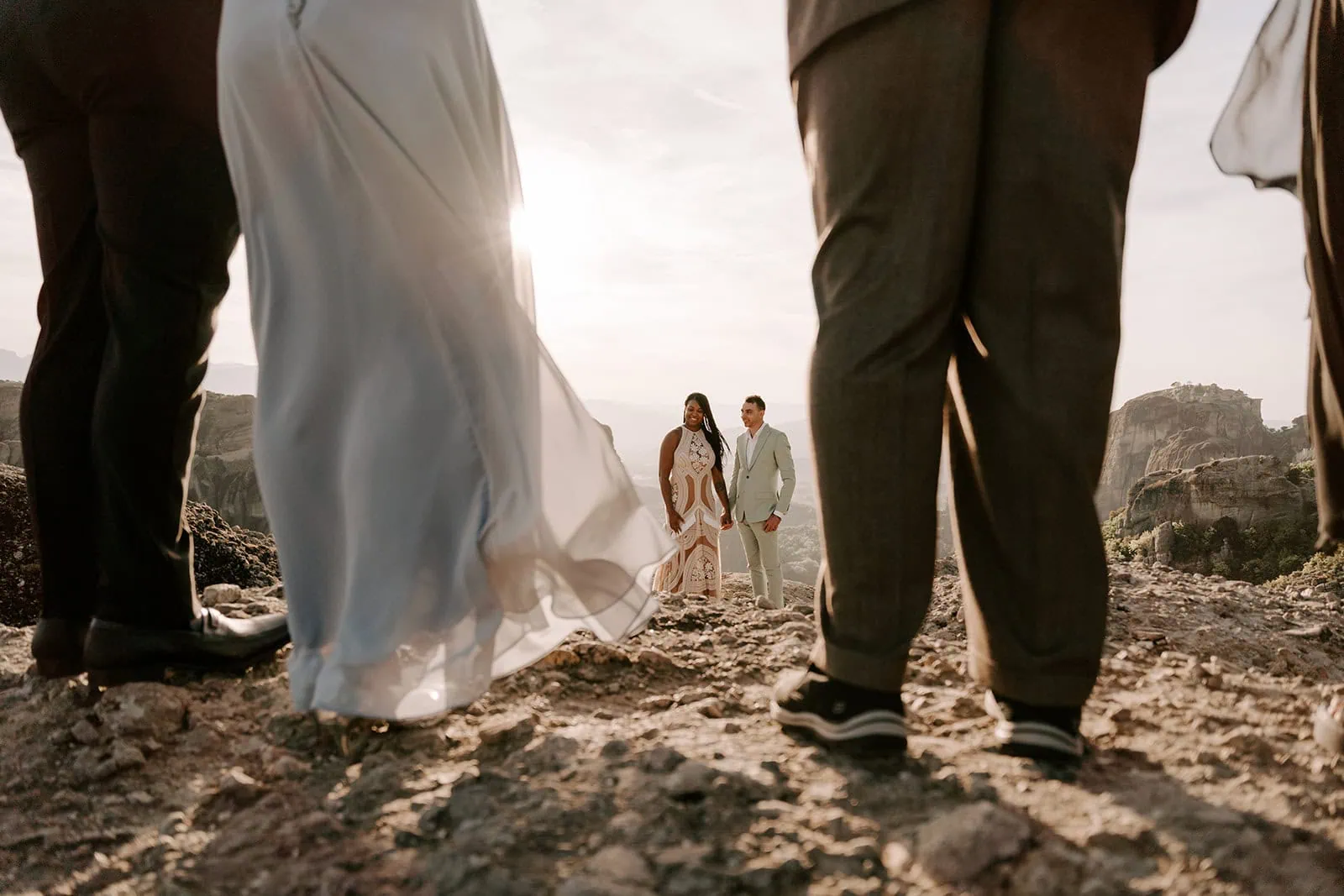 Bride and groom holding hands with a dramatic view of Meteora during their Greek mountains elopement