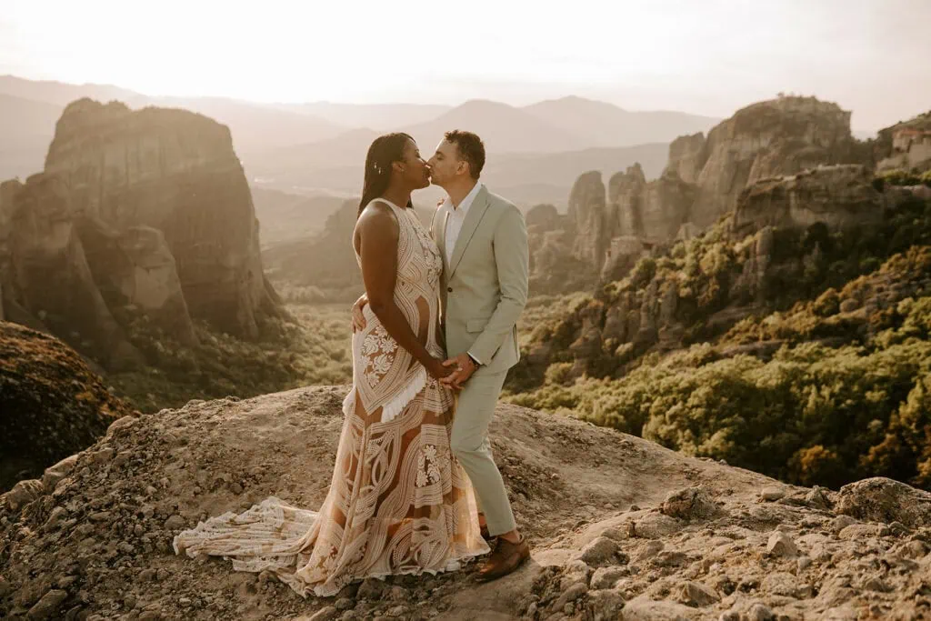 Couple sharing a kiss amidst the dramatic landscape of Meteora during their Greek mountains elopement