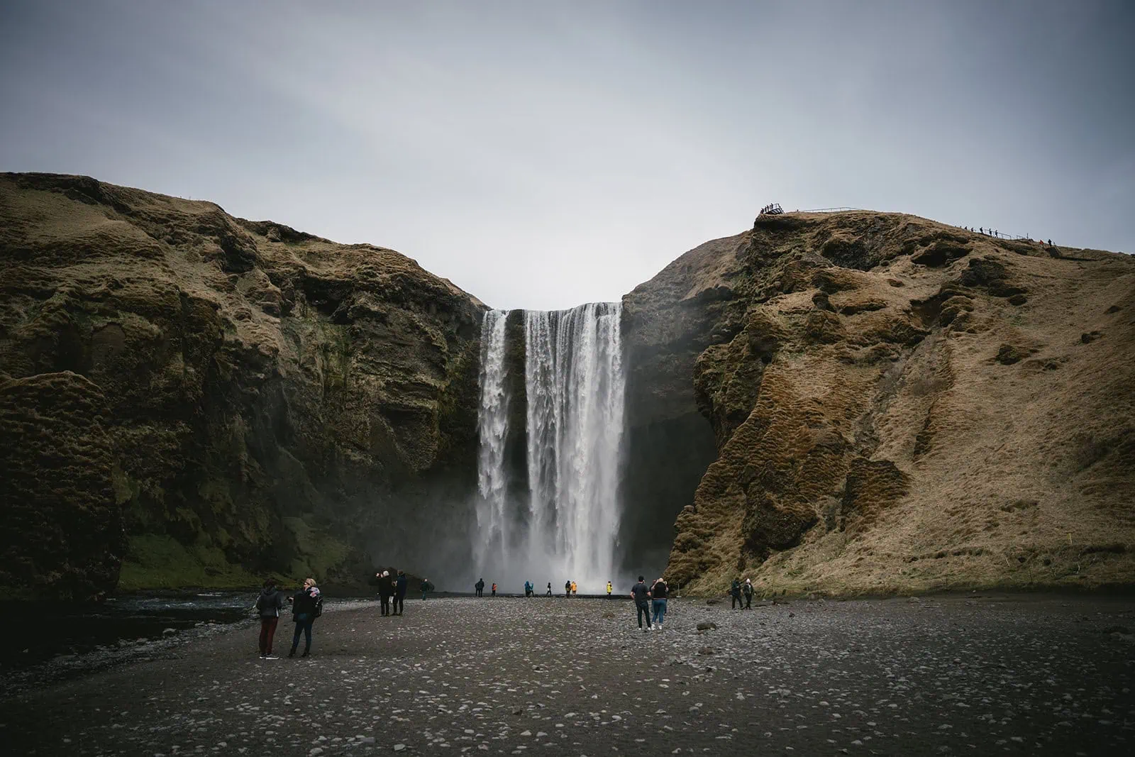 Bride and groom walking hand in hand towards the waterfall at the Mulafjulfur elopement