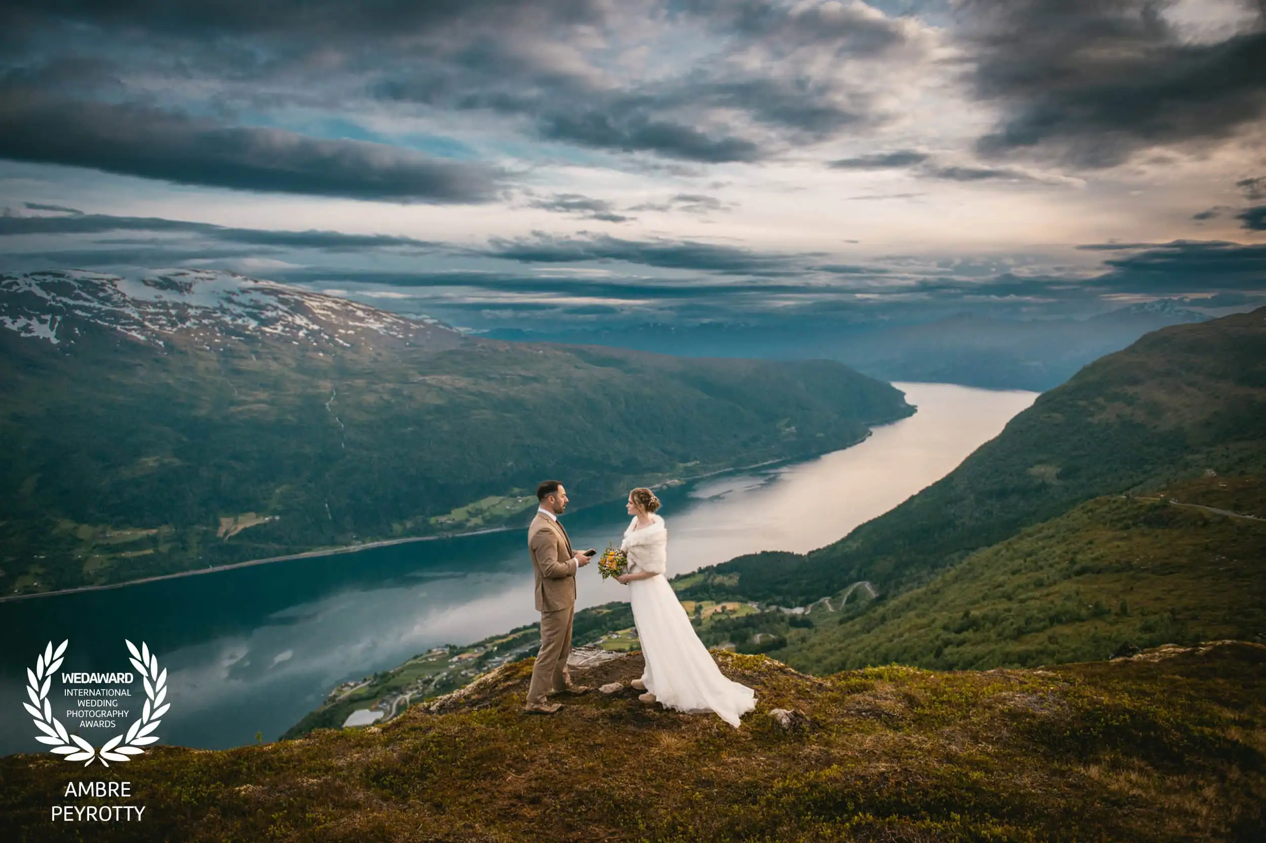 Elopement ceremony overlooking a fjord in Norway with mountains and dramatic skies.