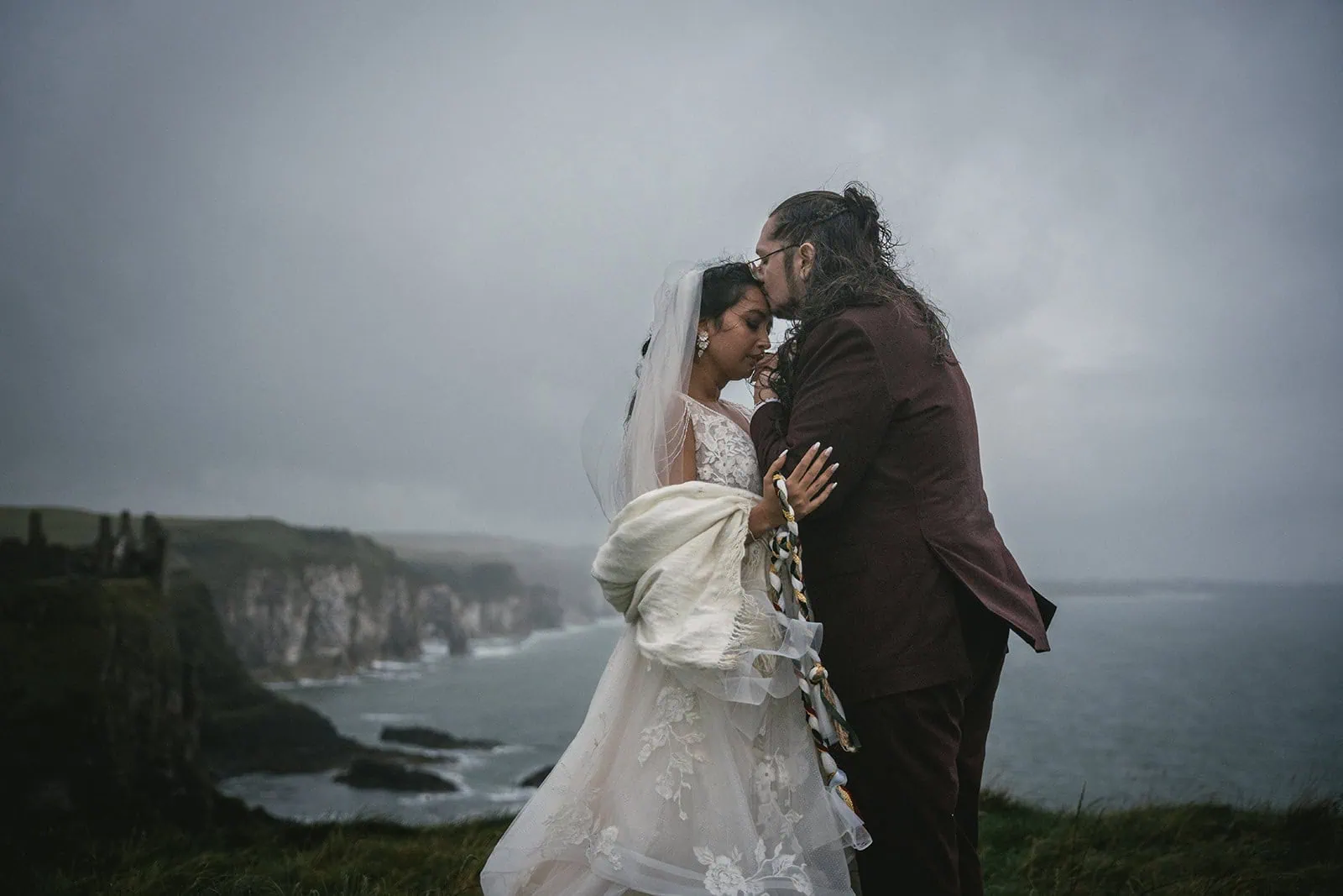 Bride and groom sharing a kiss by Dunluce Castle during their elopement